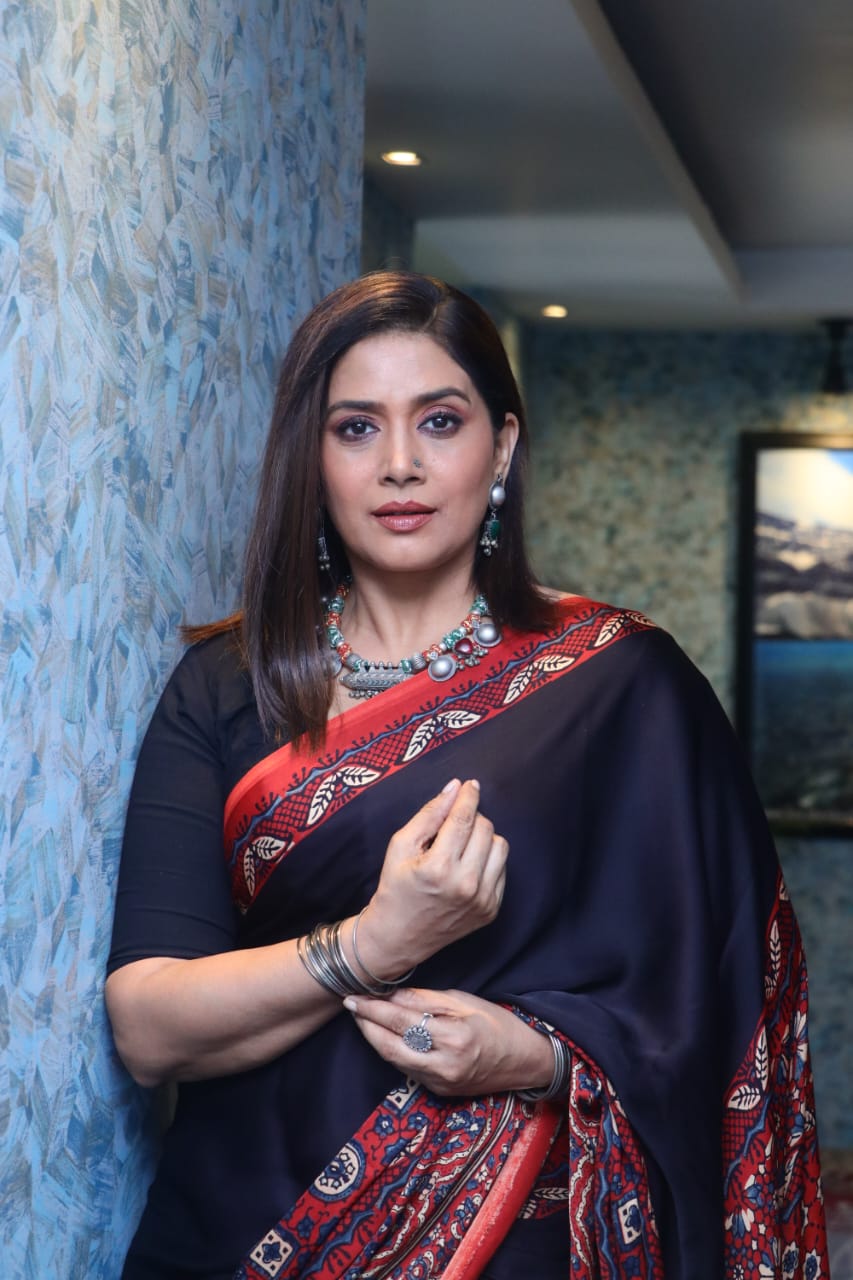 Woman wearing a black and red ajrakh saree with intricate patterns, styled with jewelry