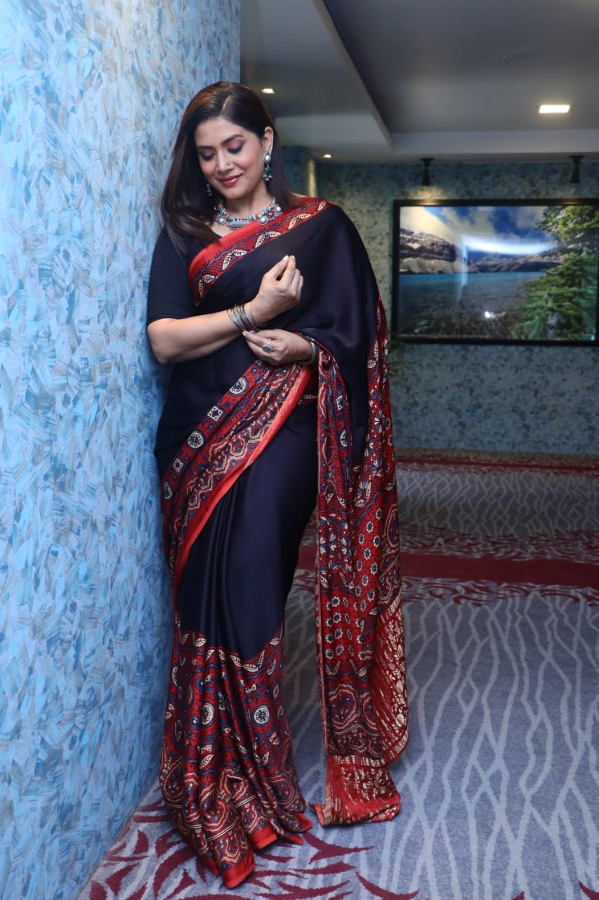 Kawaii ajrakh saree in black and red with intricate traditional patterns worn by a woman indoors