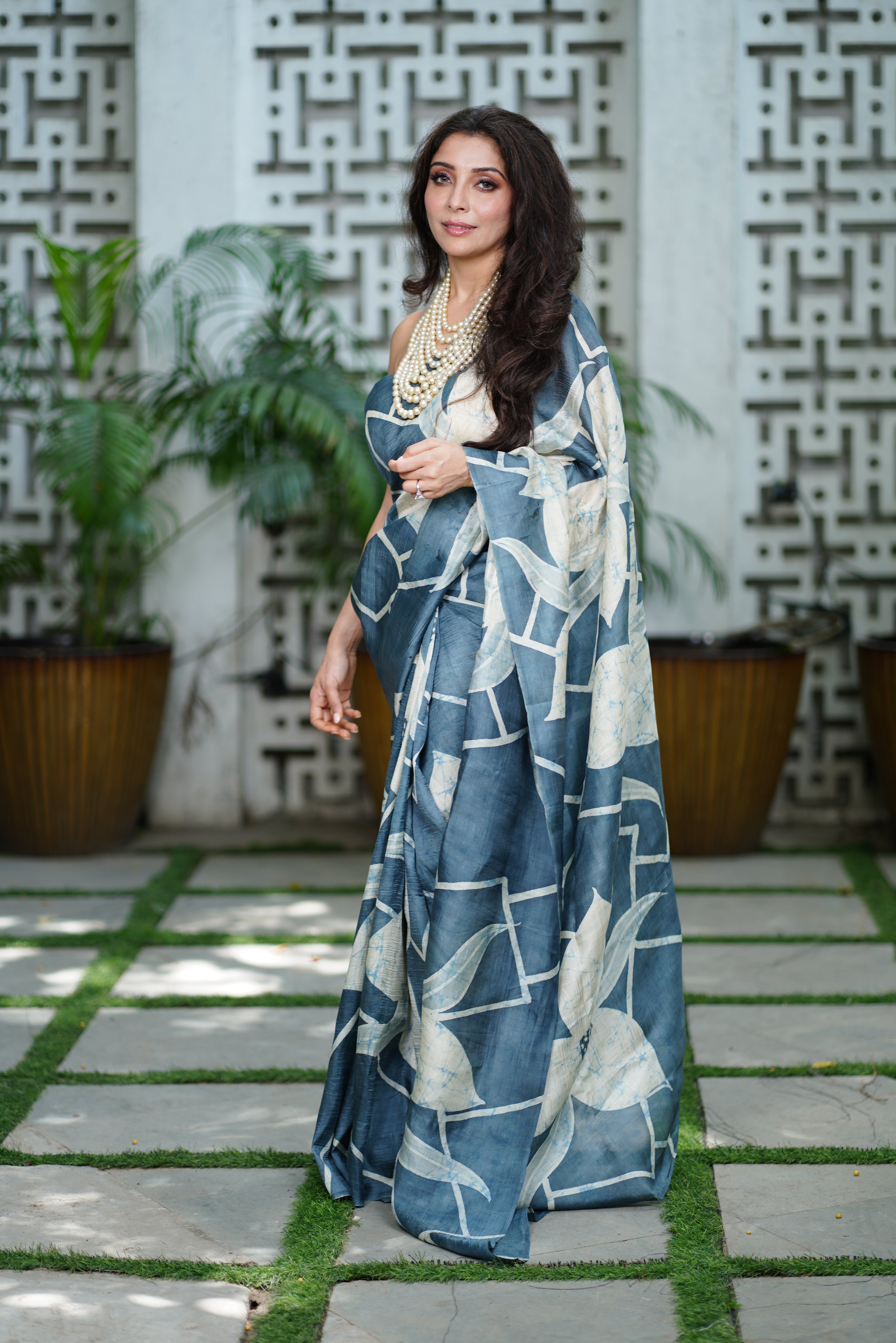 Kawaii batik saree in blue with white floral patterns worn by model in outdoor setting