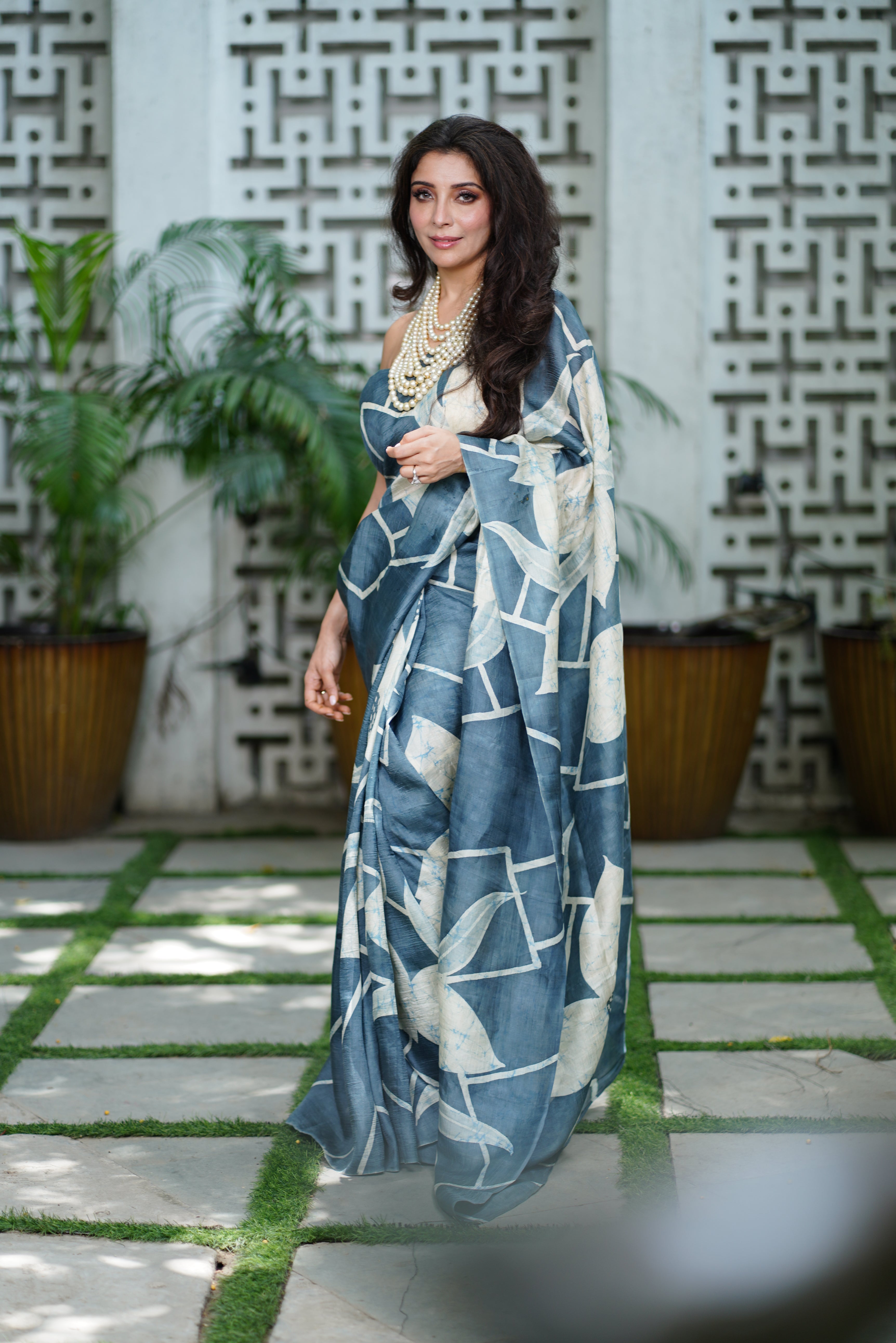 Kawaii batik saree with blue and white geometric patterns worn by woman with layered necklace outdoors