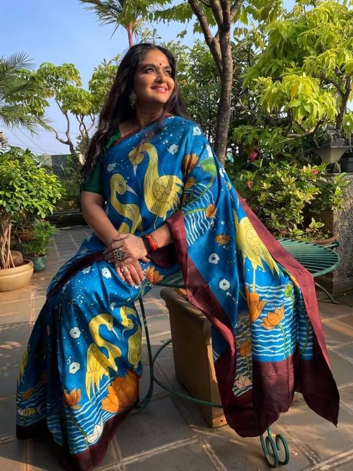 Kawaii Kalamkari batik saree in blue with yellow crane prints worn by a woman in garden