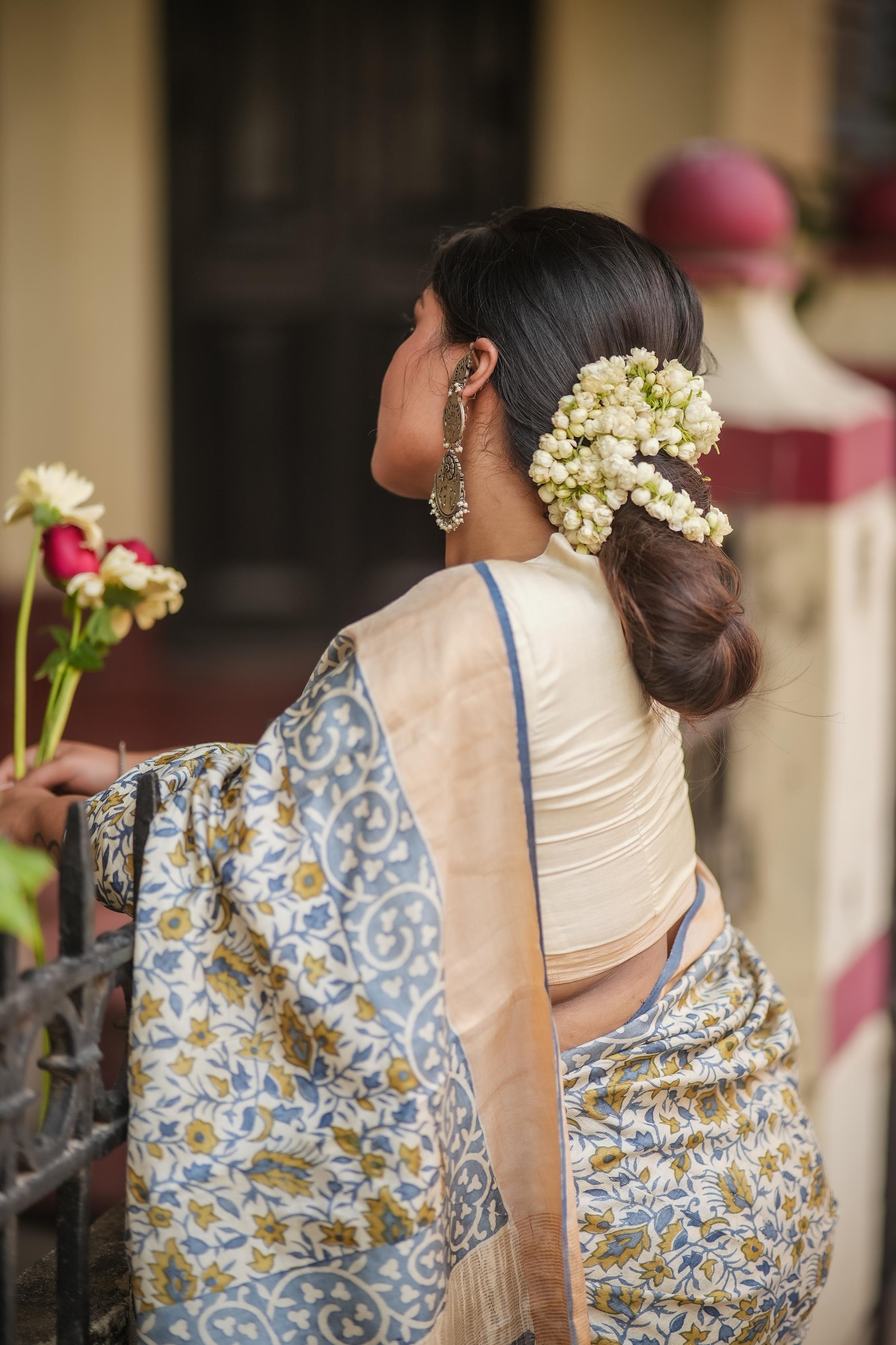 Elegant woman in a block print saree with floral designs, adorned with fresh flowers in her hair
