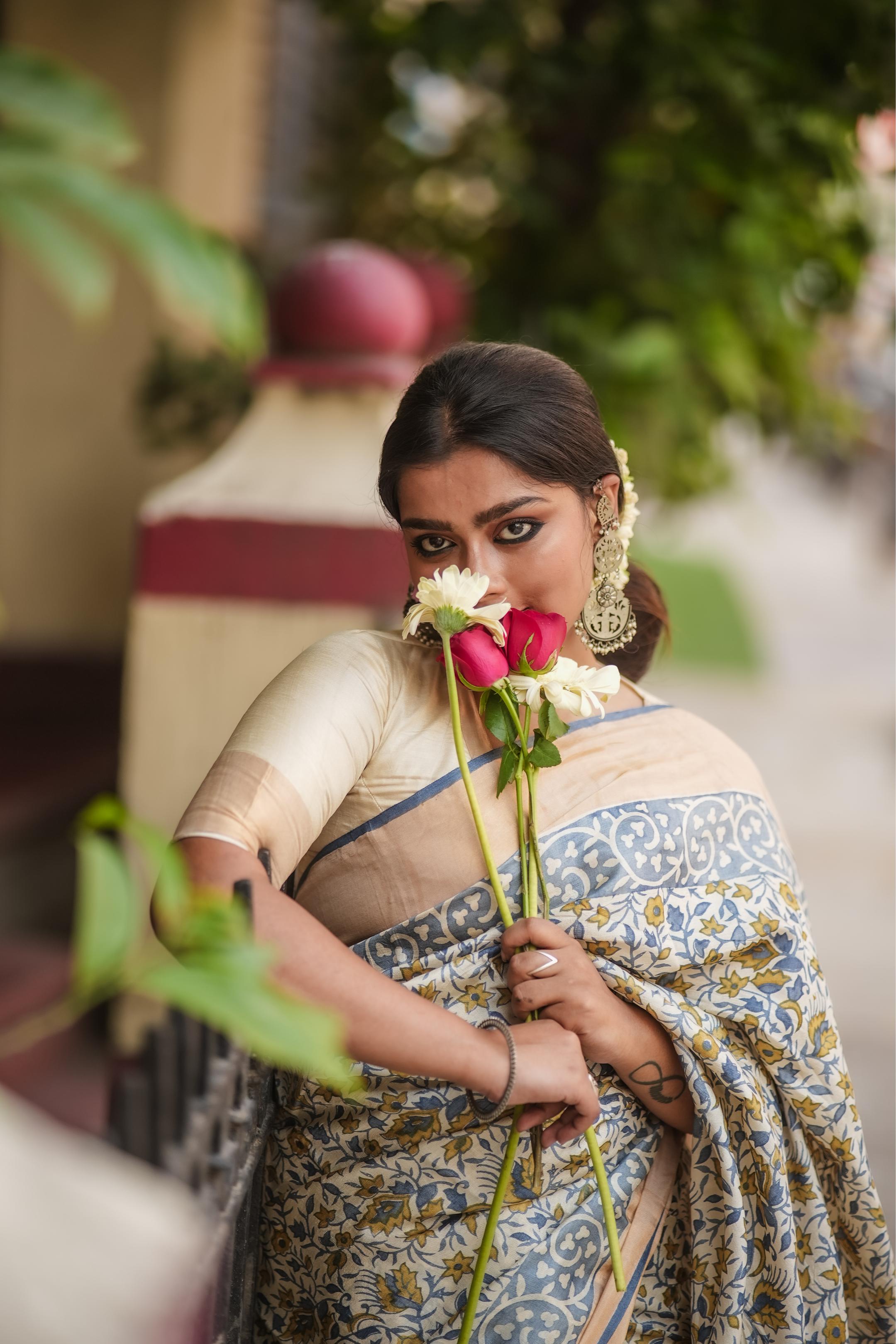 Elegant Kawaii block print saree in blue and beige worn by a woman holding flowers outdoors