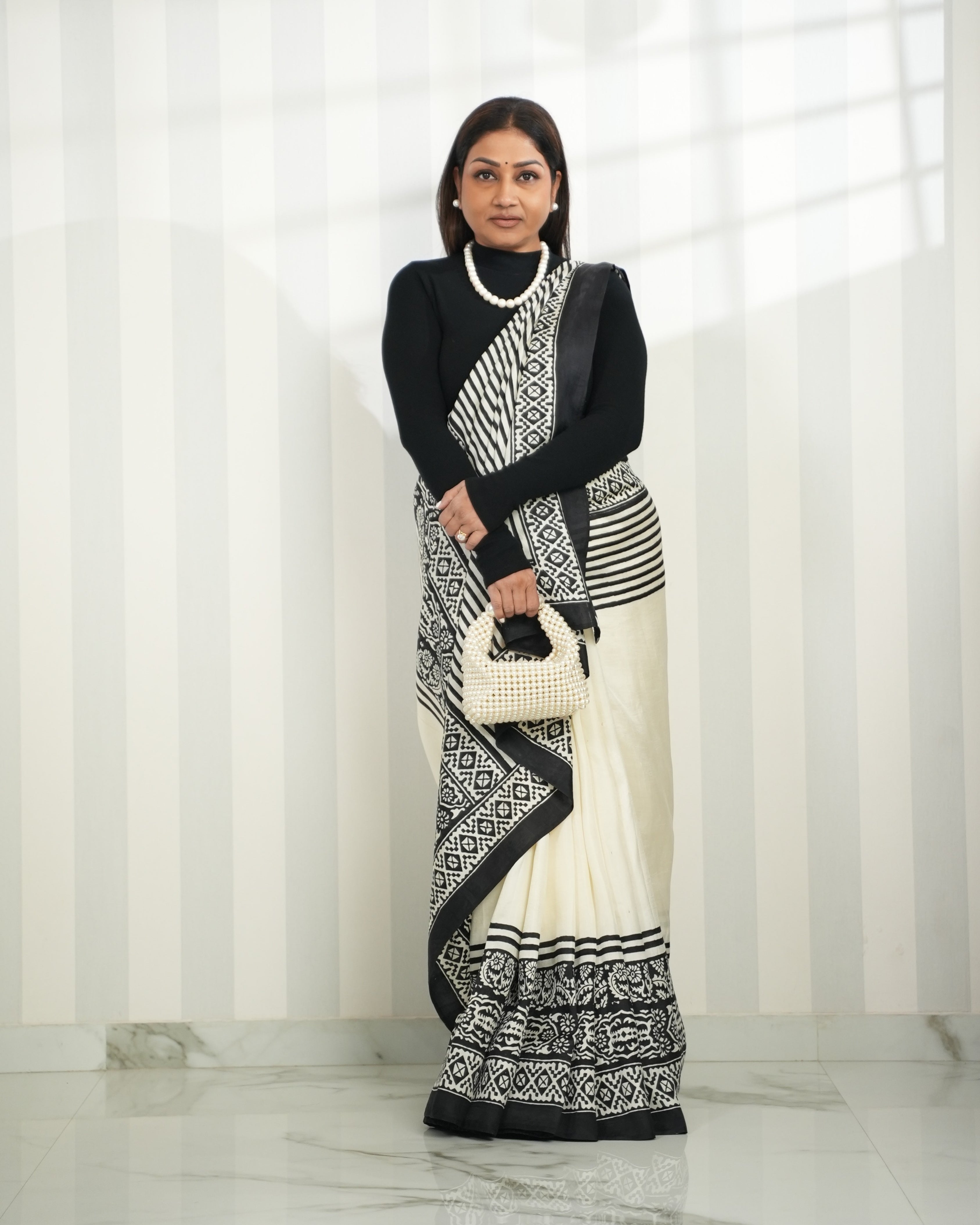 Elegant block print saree in black and white paired with a stylish handbag for a chic look