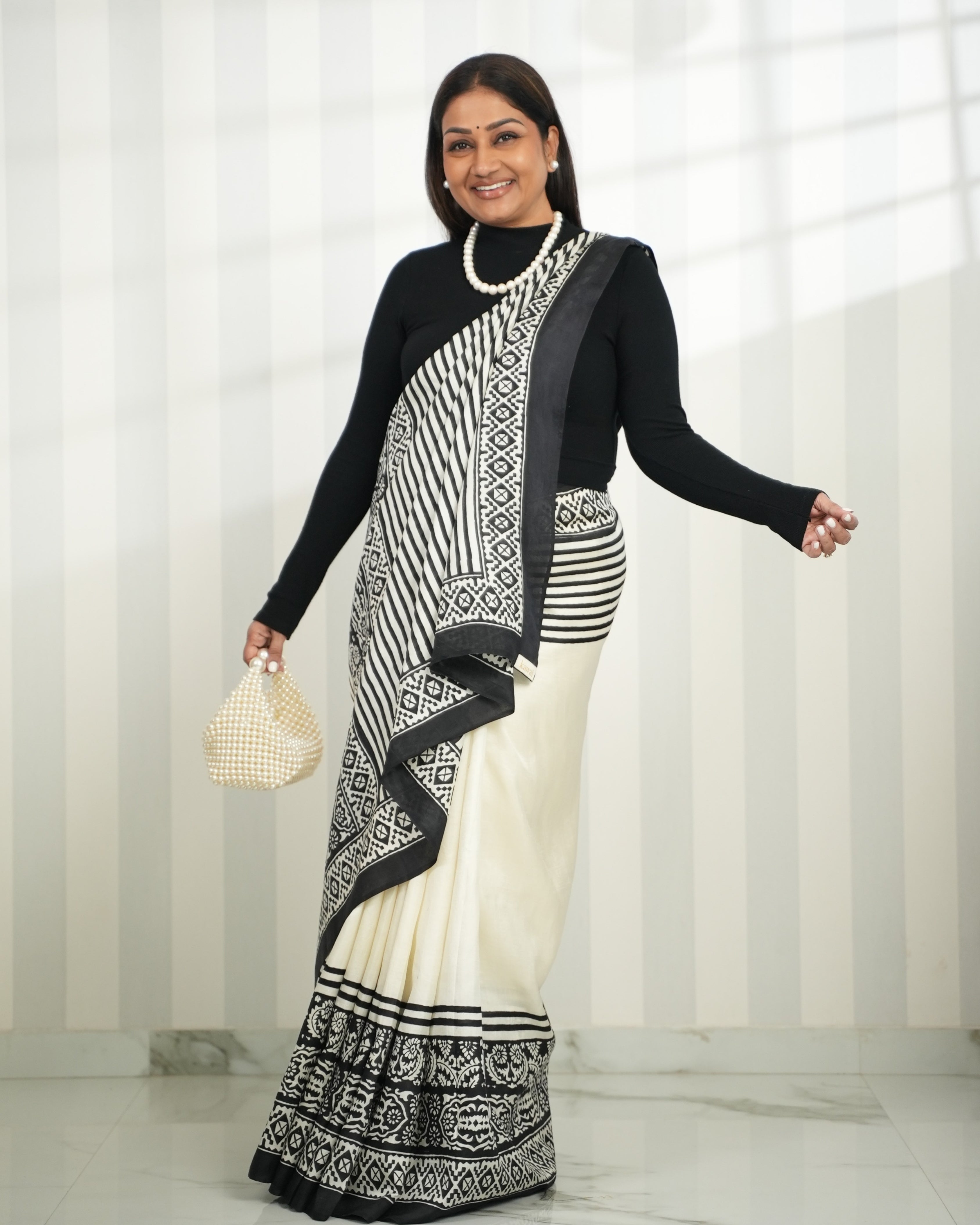 Elegant block print saree in black and white, styled with a black top and pearl accessories