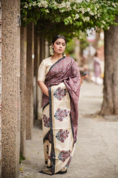 Woman wearing a traditional block print saree in cream and maroon with floral patterns and beige blouse