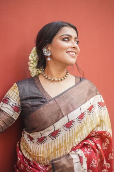 Woman wearing Kawaii block print saree with red, brown, and cream patterns and traditional jewelry