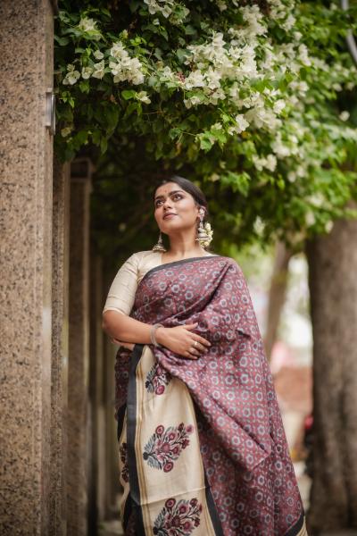 Woman wearing a Kawaii block print saree with floral patterns standing under green foliage
