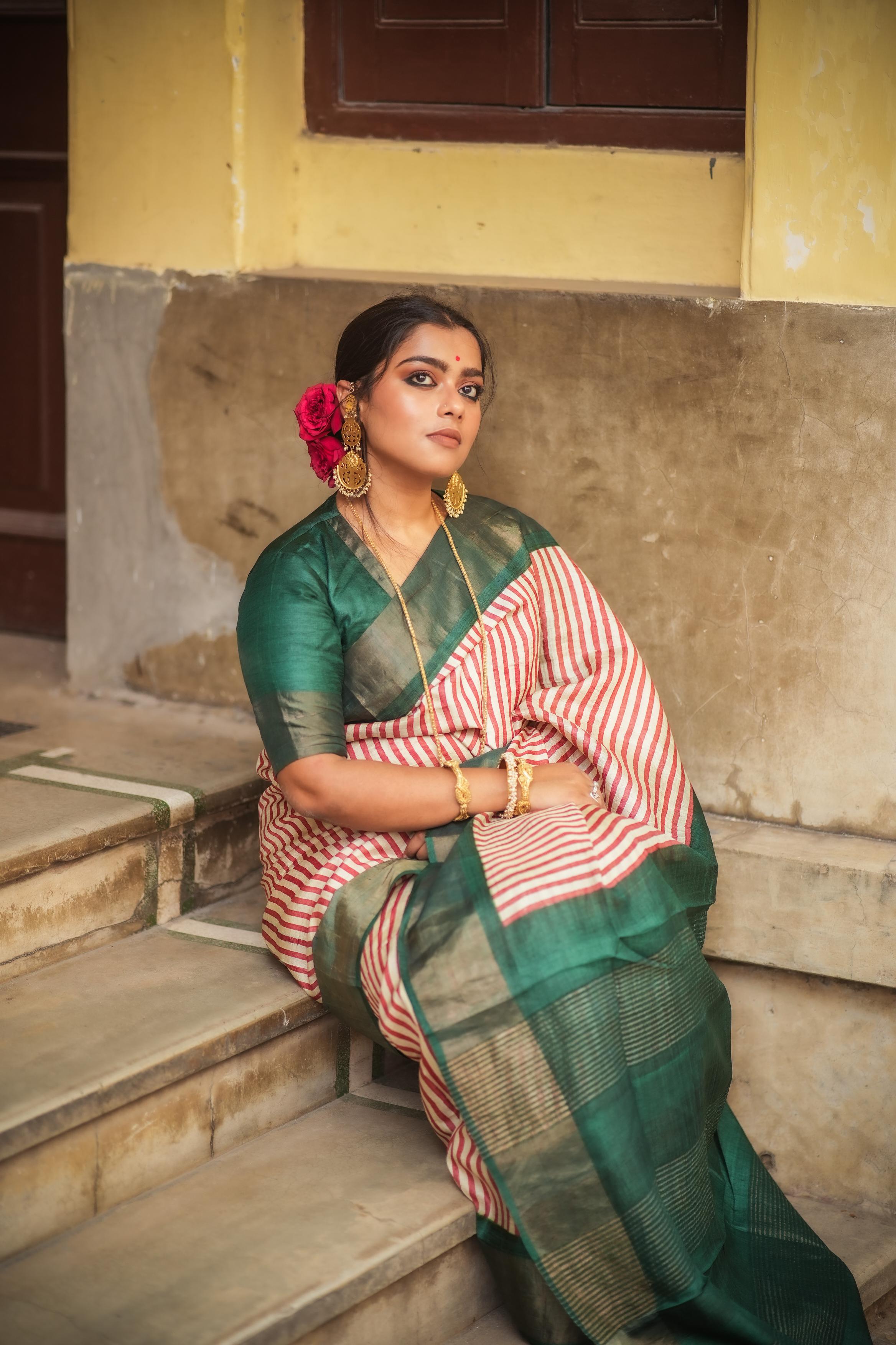 Woman wearing green and white Kawaii block print saree with gold accents sitting on steps