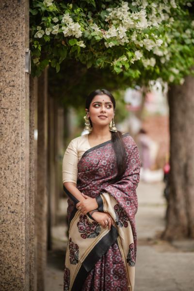 Woman wearing Kawaii block print saree with floral and paisley patterns standing outdoors under flowering tree
