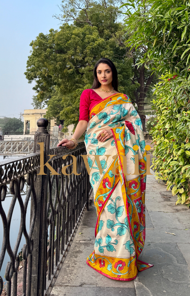 Elegant kalamkari saree in cream with vibrant floral patterns, paired with a red blouse for a traditional look