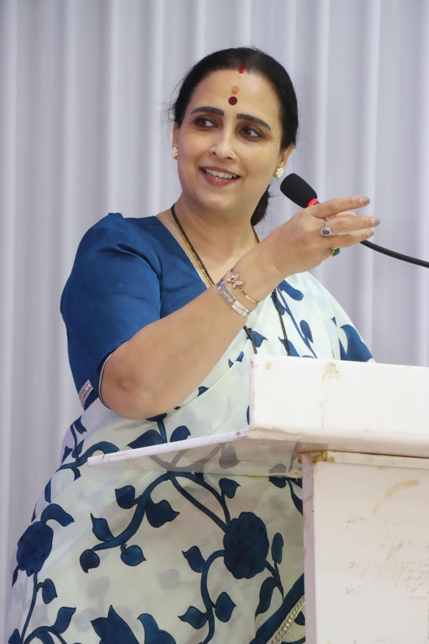 Woman wearing blue and white kalamkari saree by Kawaii speaking at podium with microphone