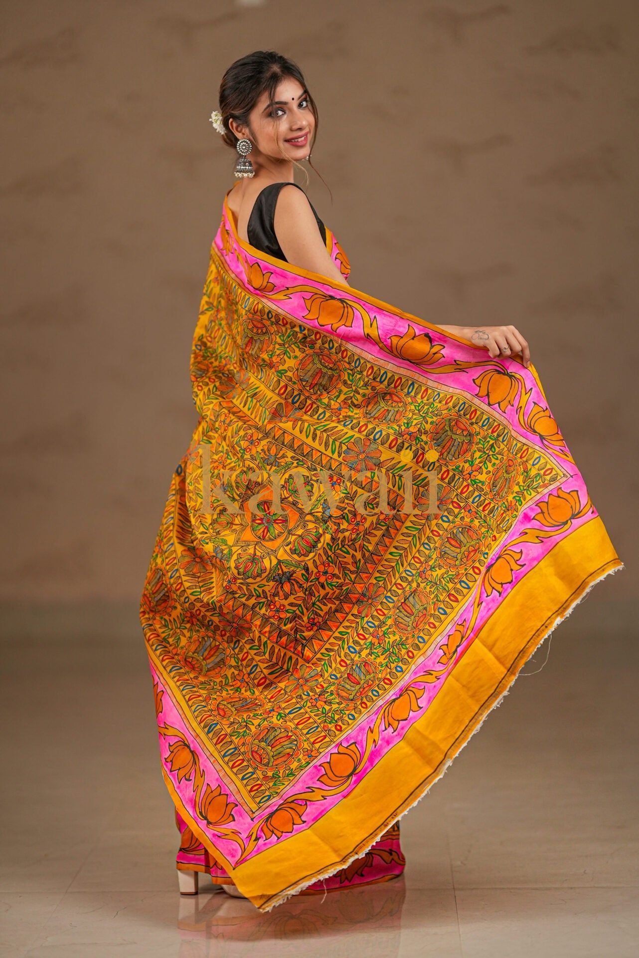 Vibrant kalamkari saree with intricate floral patterns in green, orange, and pink featuring light fabric