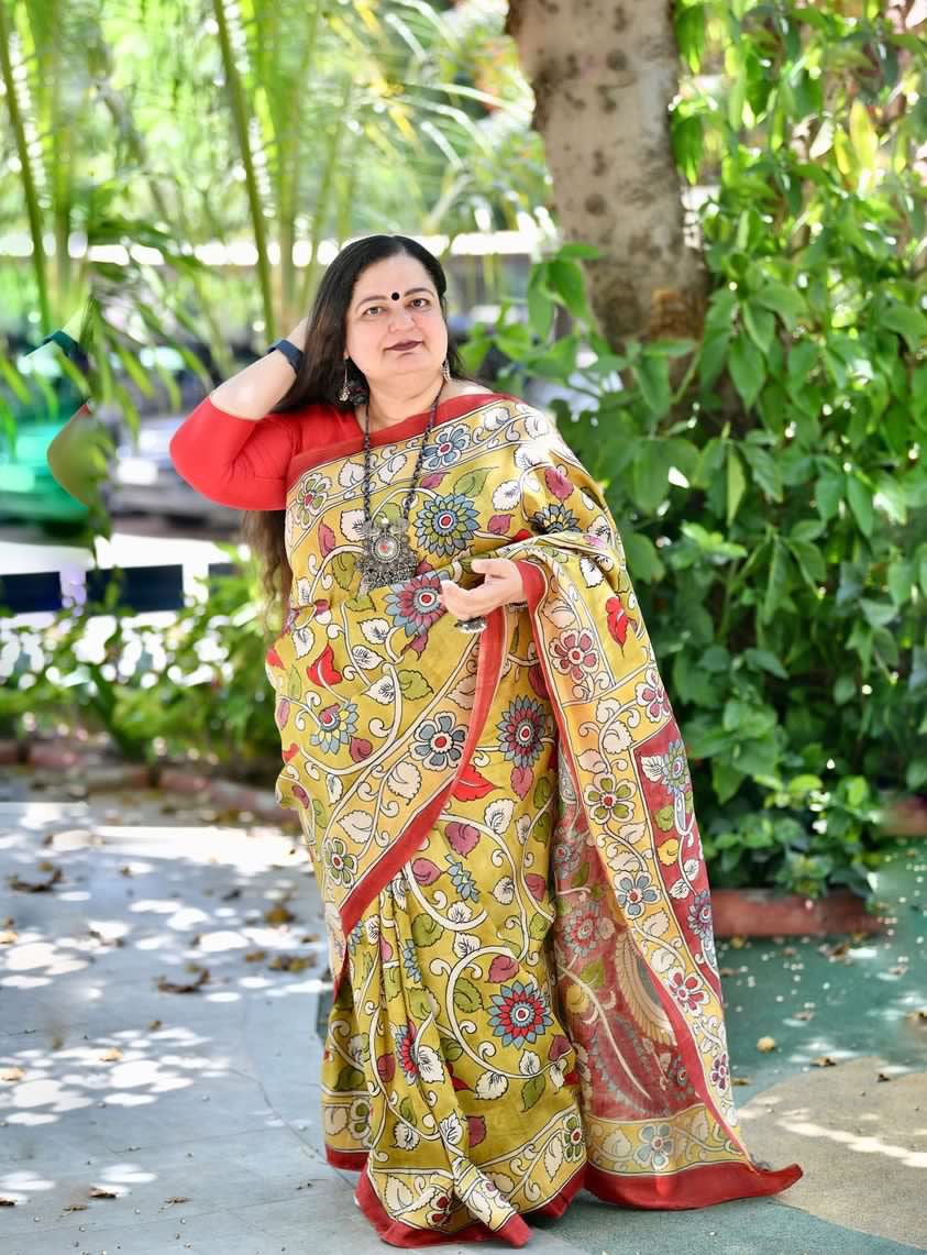 Woman wearing a yellow and red floral patterned kalamkari saree from Kawaii outdoors in natural light