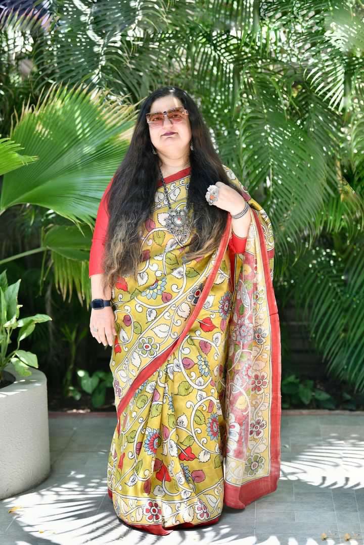 Woman wearing Kawaii kalamkari saree with traditional floral patterns and red border outdoors