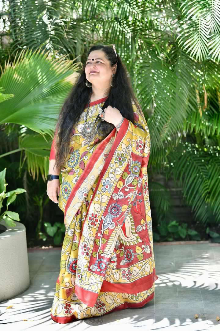 Kawaii kalamkari saree with vibrant floral and bird motifs worn by woman standing outdoors