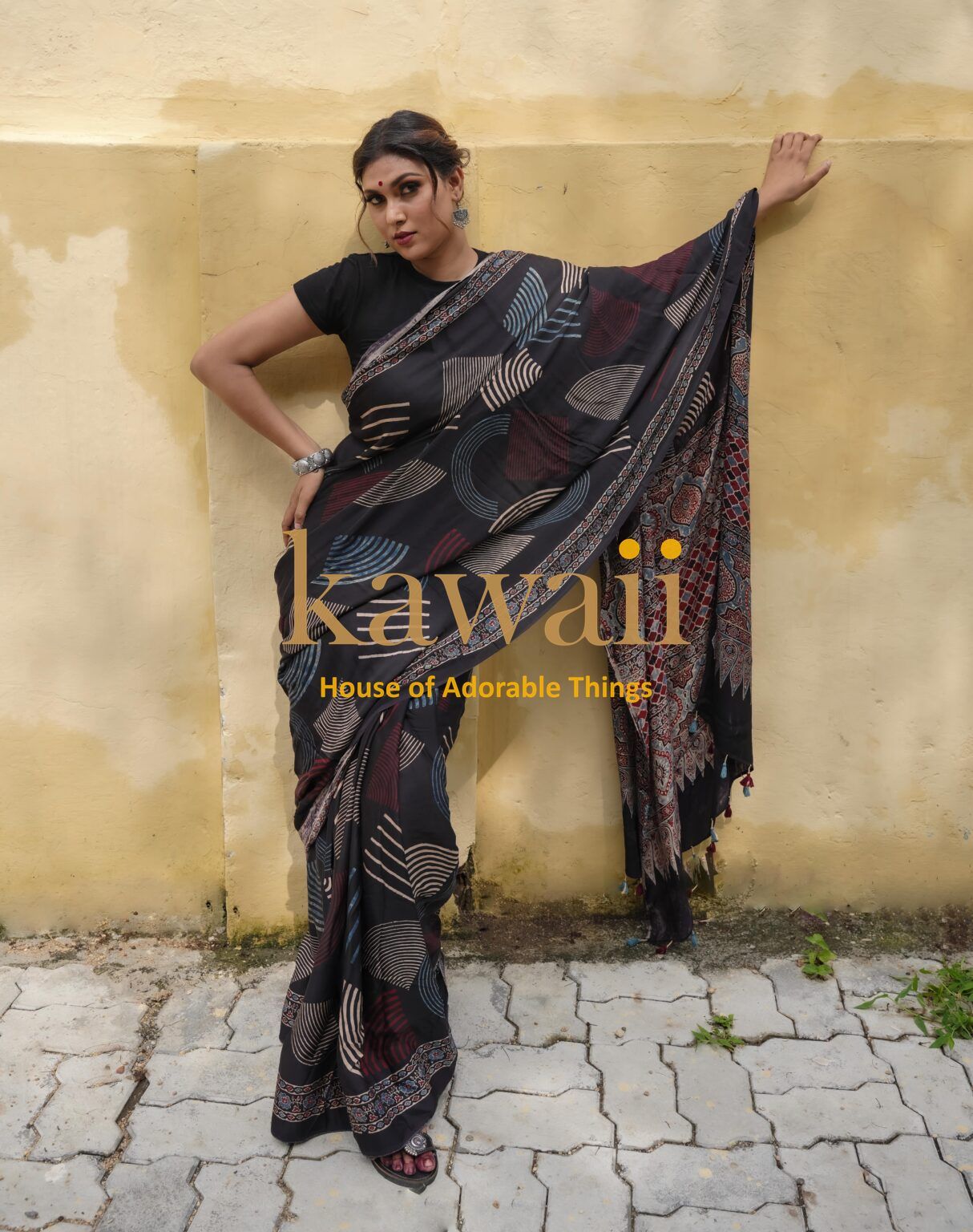 Kawaii ajrakh saree in black with multicolor abstract patterns worn by woman posing against yellow wall