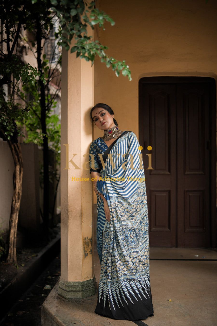 Elegant blue and white ajrakh saree worn by woman standing near pillar outdoors