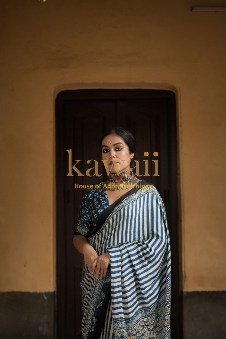 Woman wearing a traditional blue and white striped ajrakh saree by Kawaii with intricate patterns