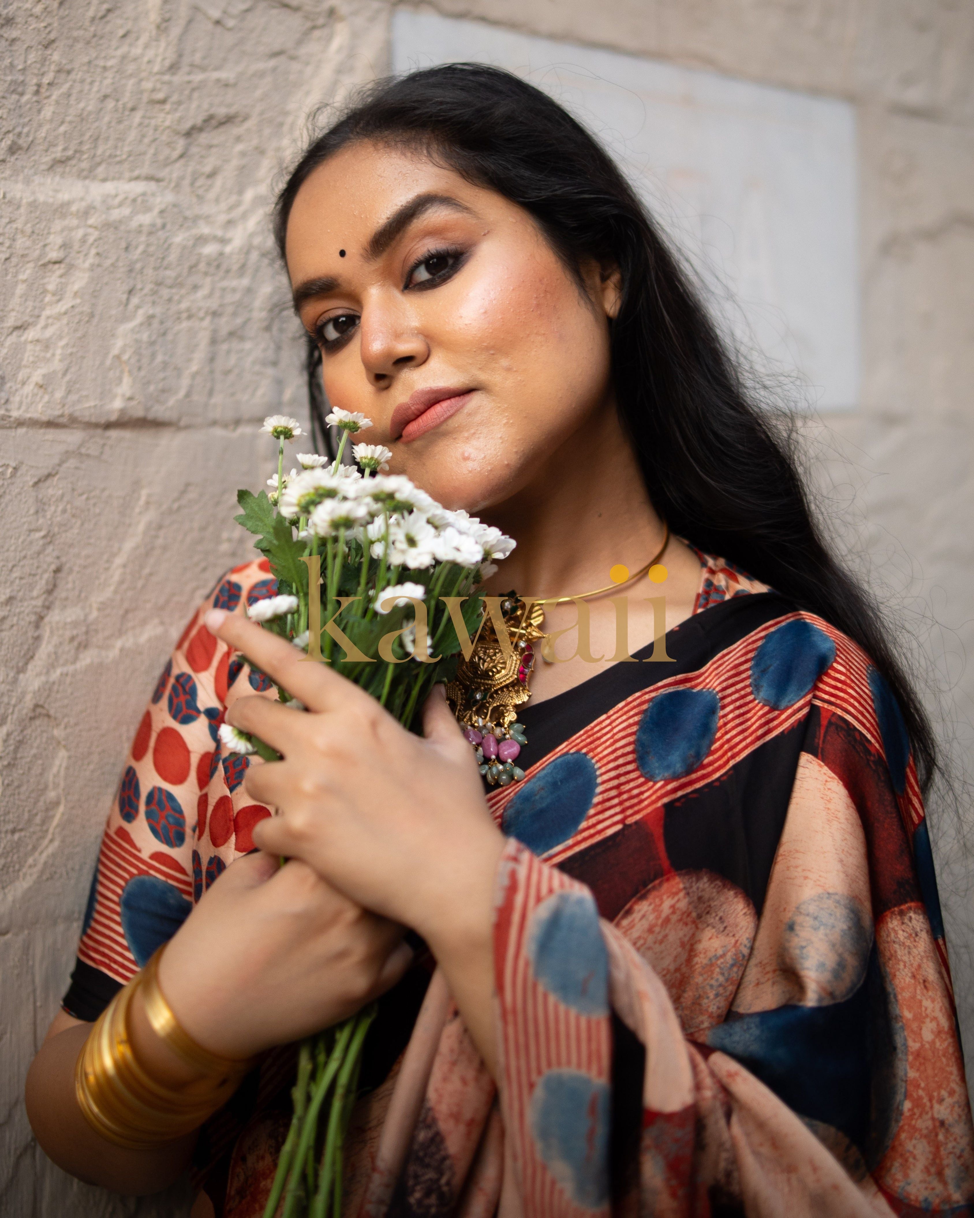Woman wearing a Kawaii ajrakh saree holding white flowers with traditional jewelry