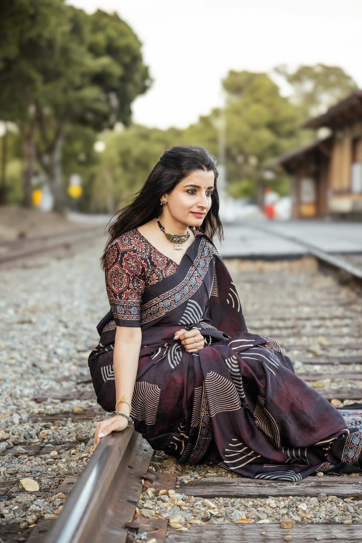 Woman wearing Kawaii ajrakh saree with traditional patterns sitting on railway tracks outdoors