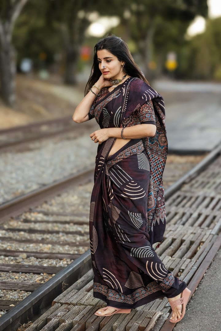 Woman wearing a patterned ajrakh saree by Kawaii standing on railway tracks outdoors