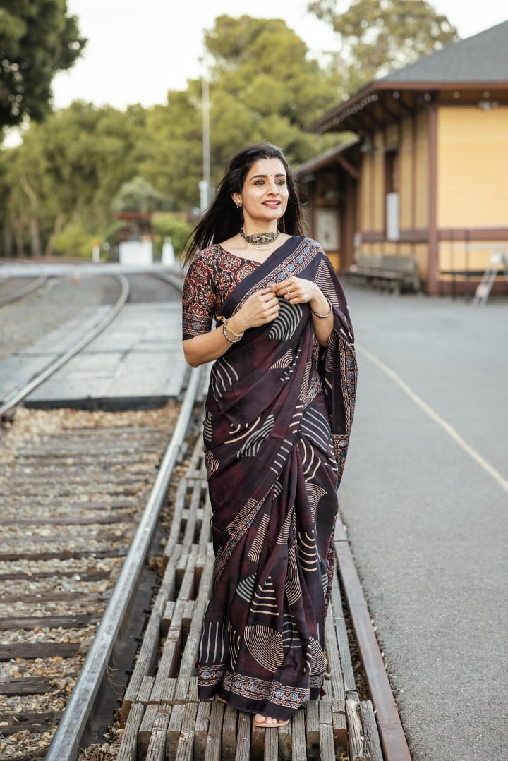 Woman wearing a black and brown ajrakh saree by Kawaii walking on railway tracks outdoors
