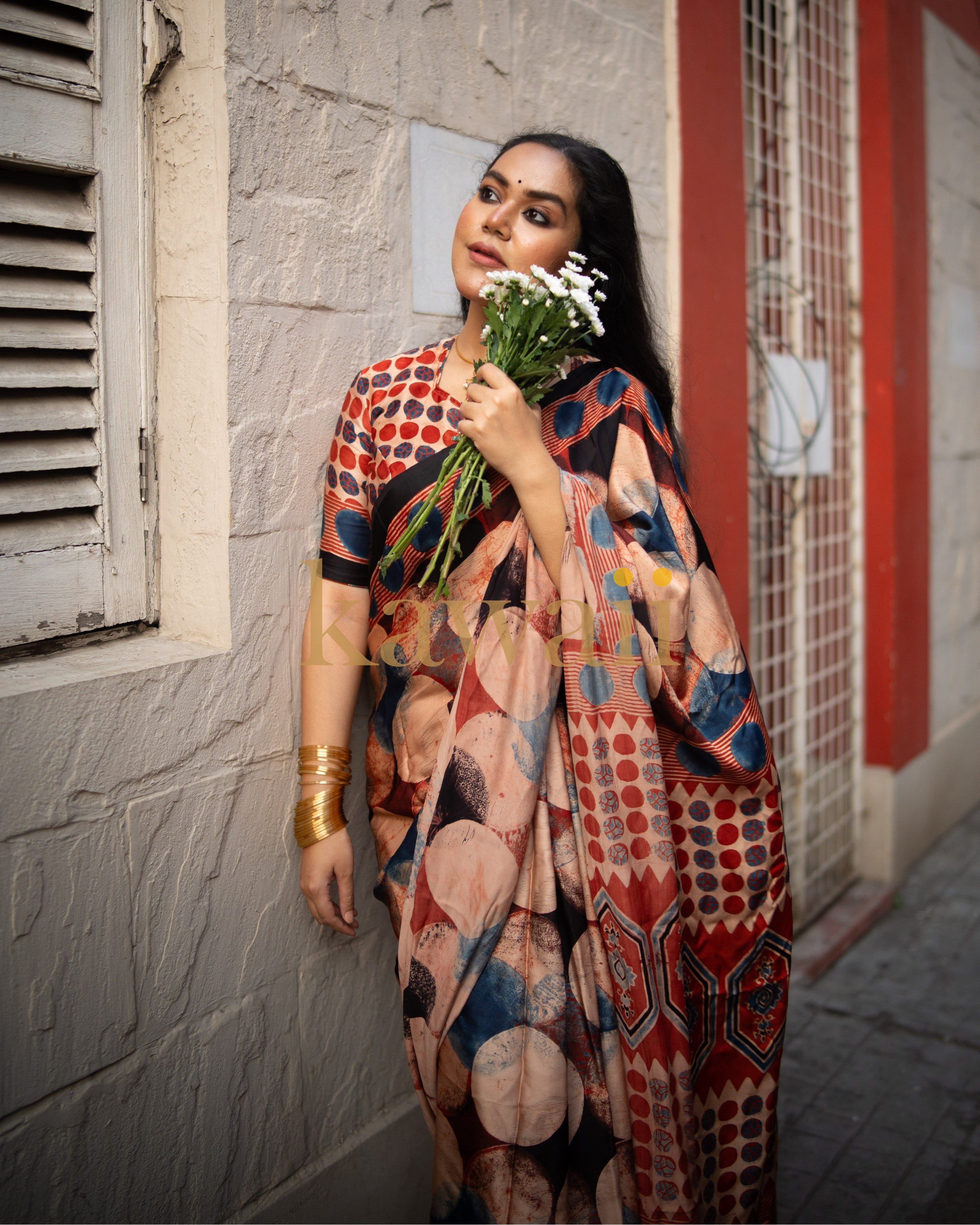 Woman wearing colorful ajrakh saree from Kawaii holding white flowers by a textured wall