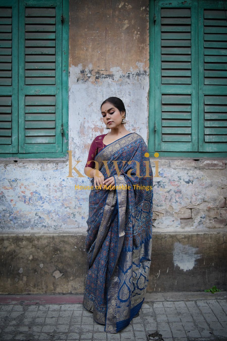 Woman wearing a blue and gold traditional ajrakh saree from Kawaii standing against a rustic wall
