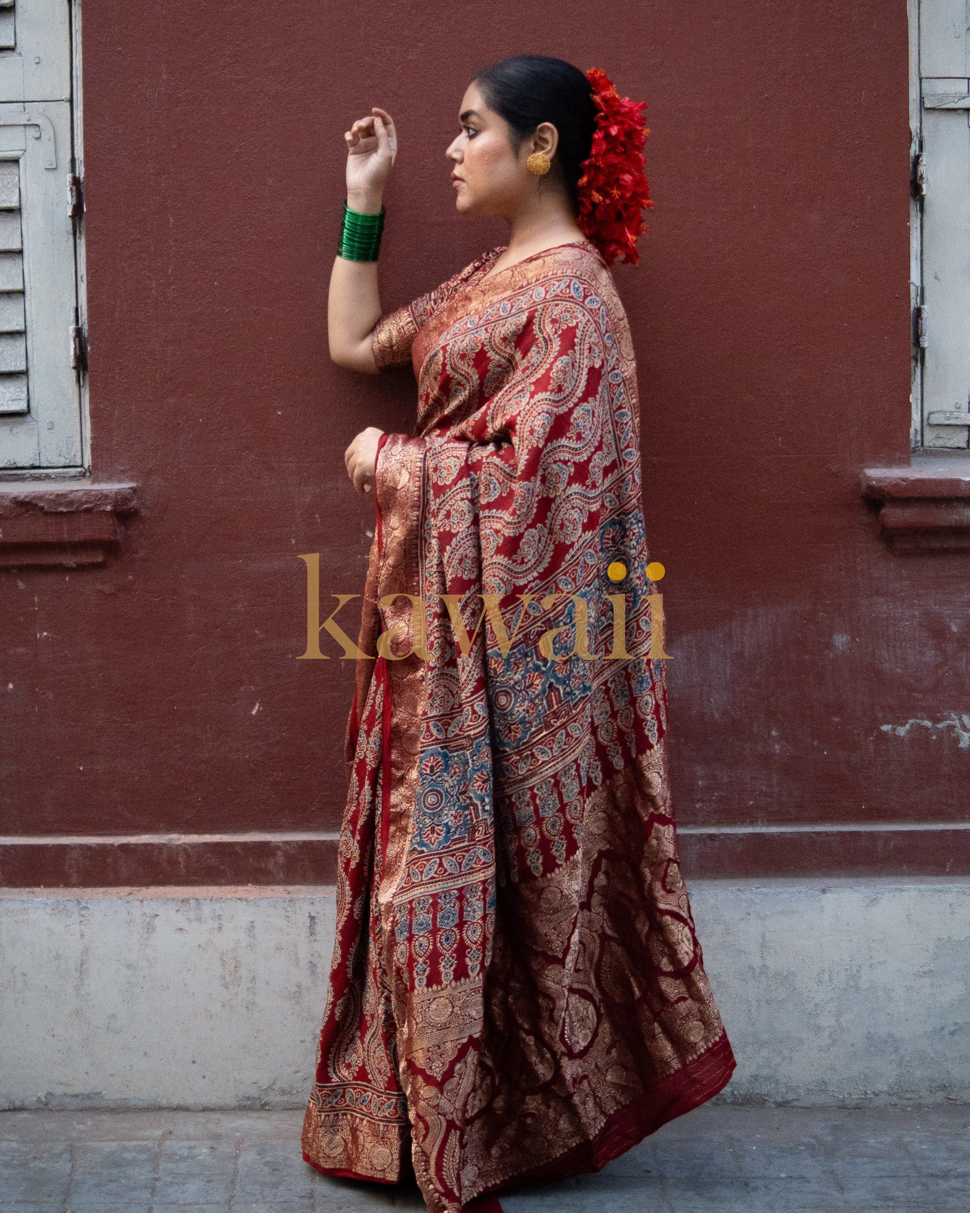 Kawaii ajrakh saree in red and gold with intricate traditional patterns worn by woman with flower hair accessory