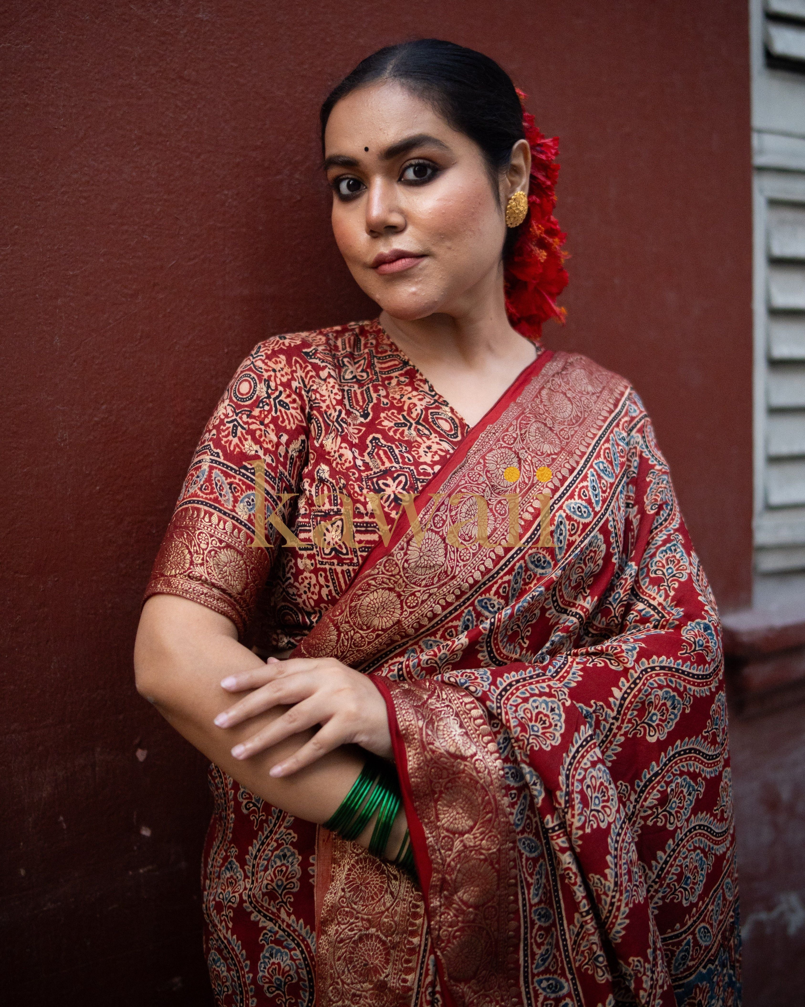 Woman wearing a red and gold ajrakh saree with intricate traditional patterns and green bangles