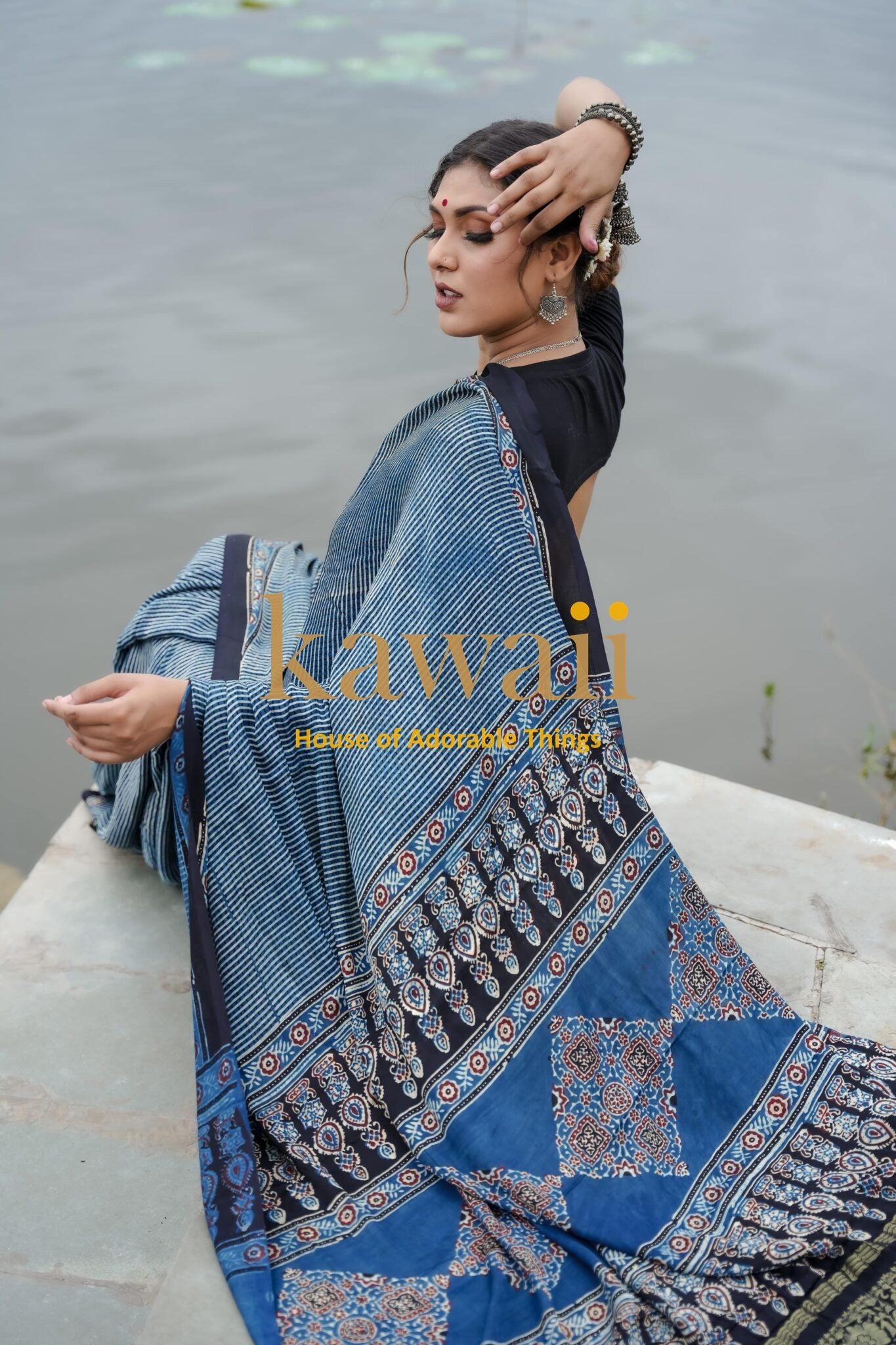 Kawaii ajrakh saree in blue with traditional patterns worn by woman near water, ajrakh sarees online