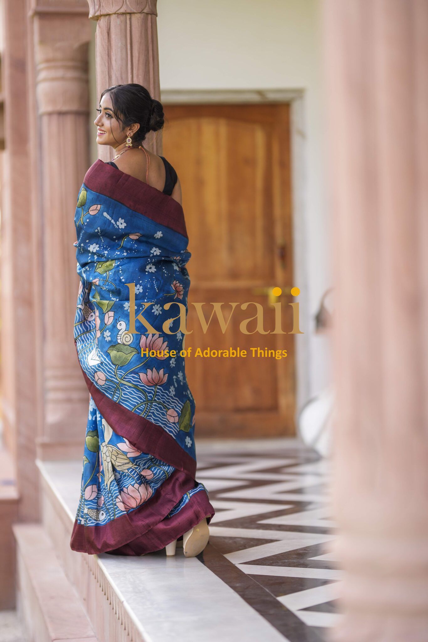 Kawaii blue Kalamkari batik saree with floral patterns worn by woman in elegant setting
