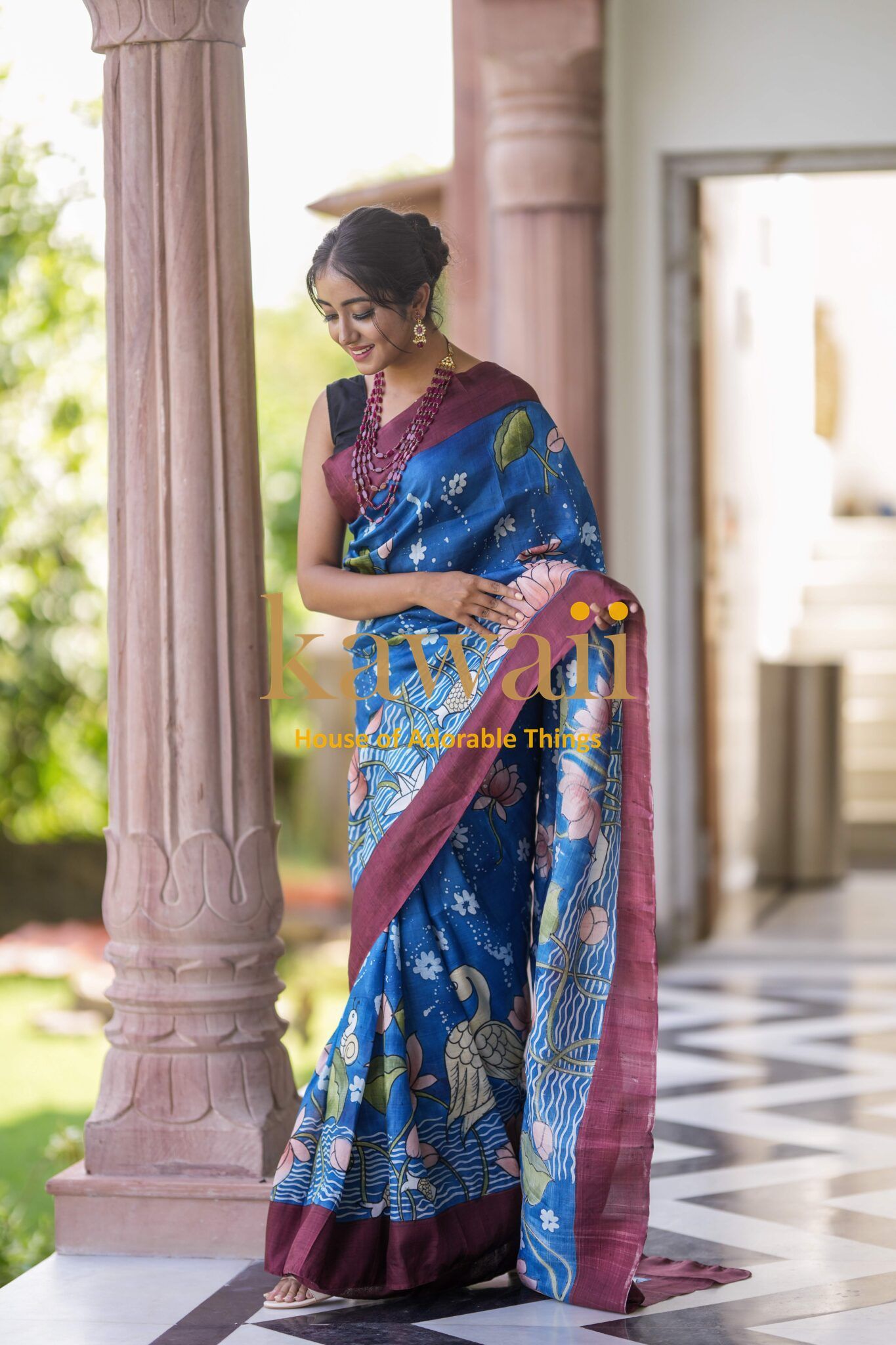 Kawaii Kalamkari batik saree in blue with maroon border worn by woman in traditional setting