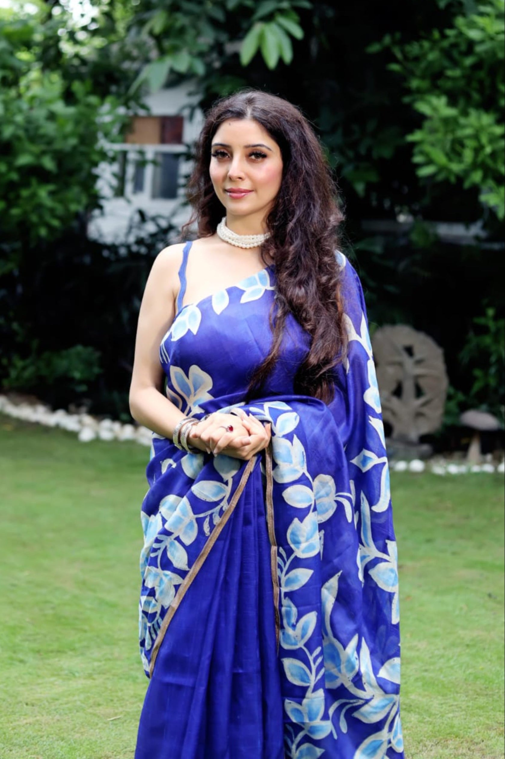 Woman wearing a blue floral batik saree by Kawaii standing outdoors on grass