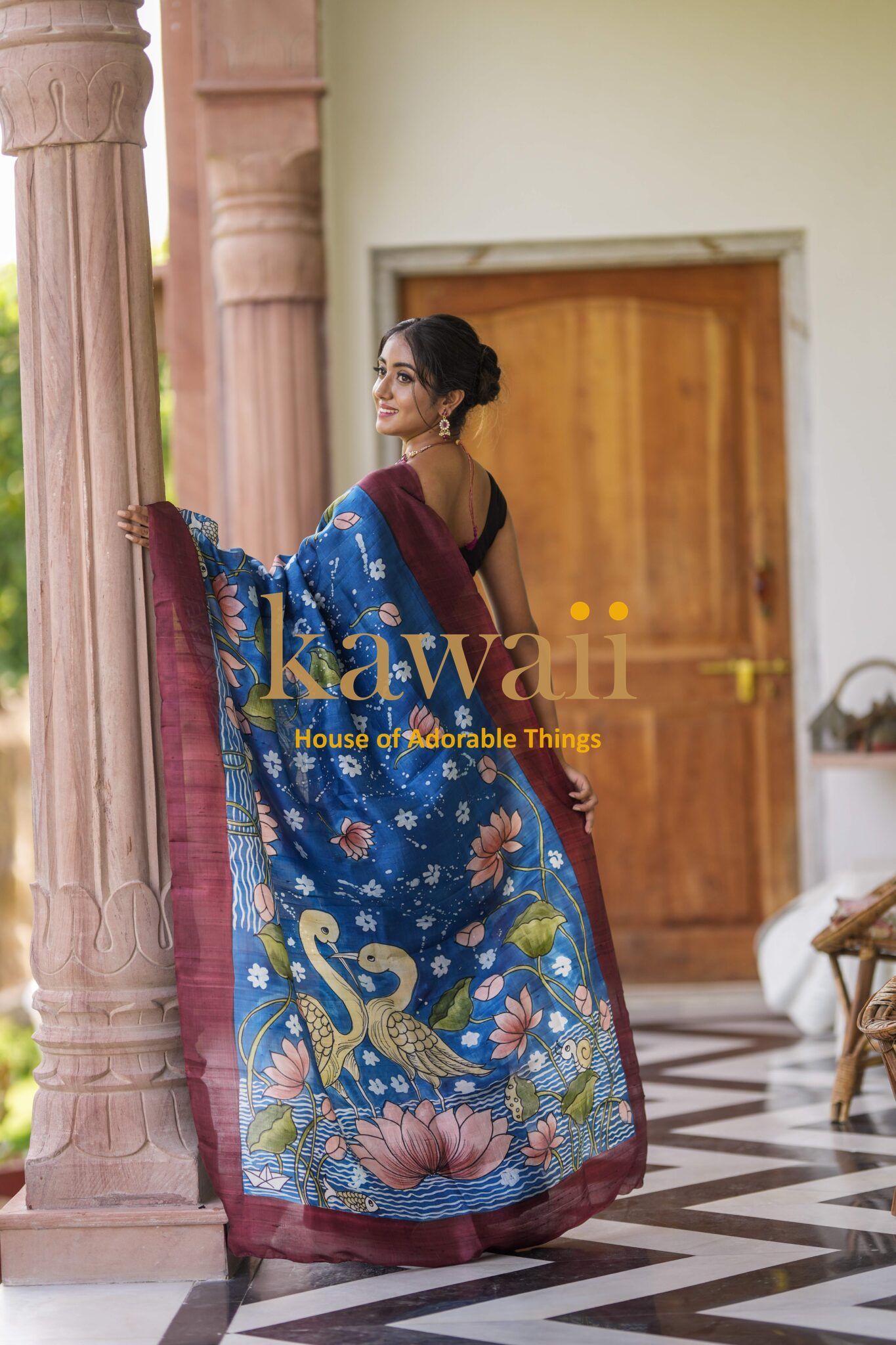 Kawaii Kalamkari batik saree in blue with floral and peacock designs worn by a woman indoors