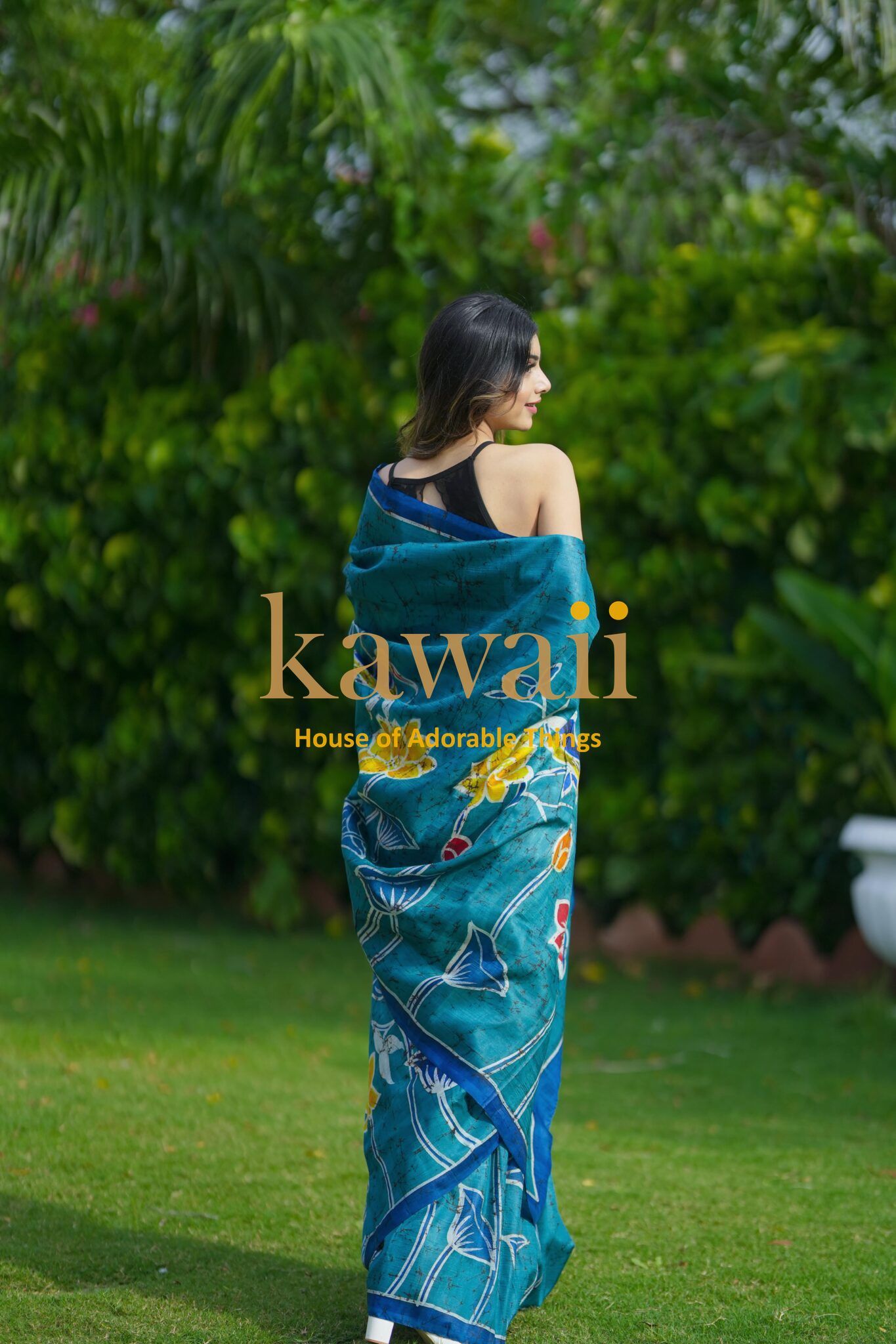 Kawaii batik saree with intricate blue and yellow floral patterns worn by woman in garden