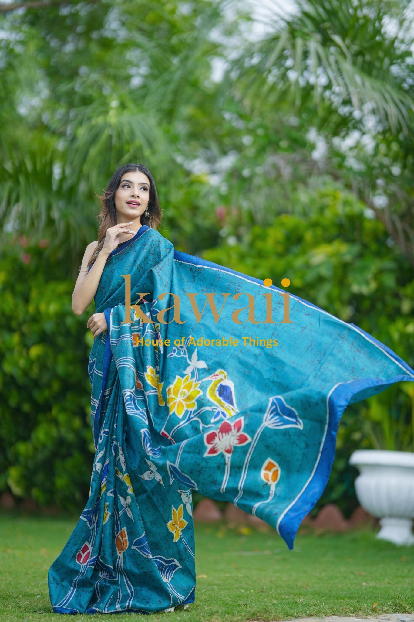 Woman wearing blue floral batik saree by Kawaii in a garden setting