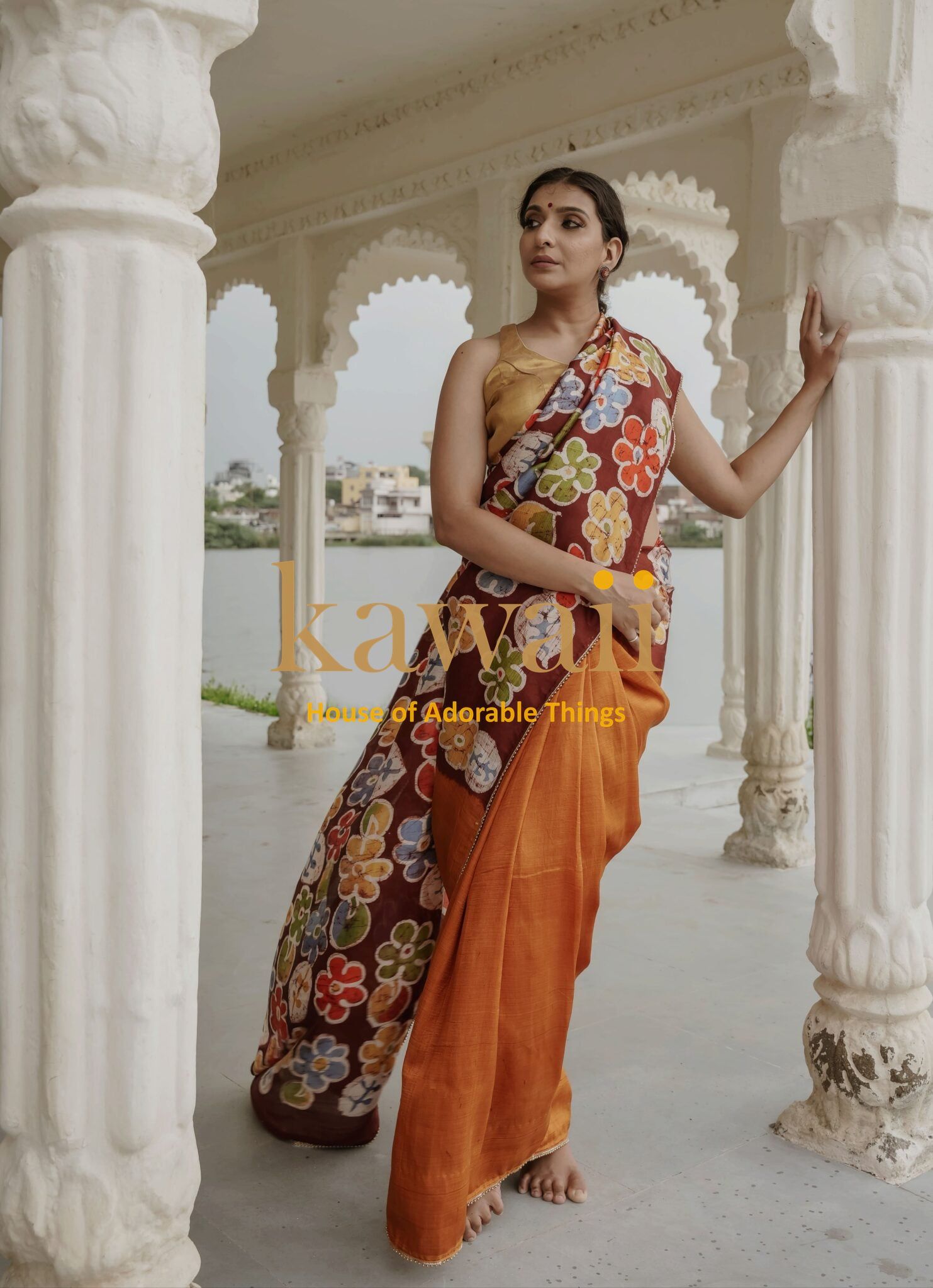 Woman wearing Kawaii batik saree with colorful floral design and orange pallu in an architectural setting