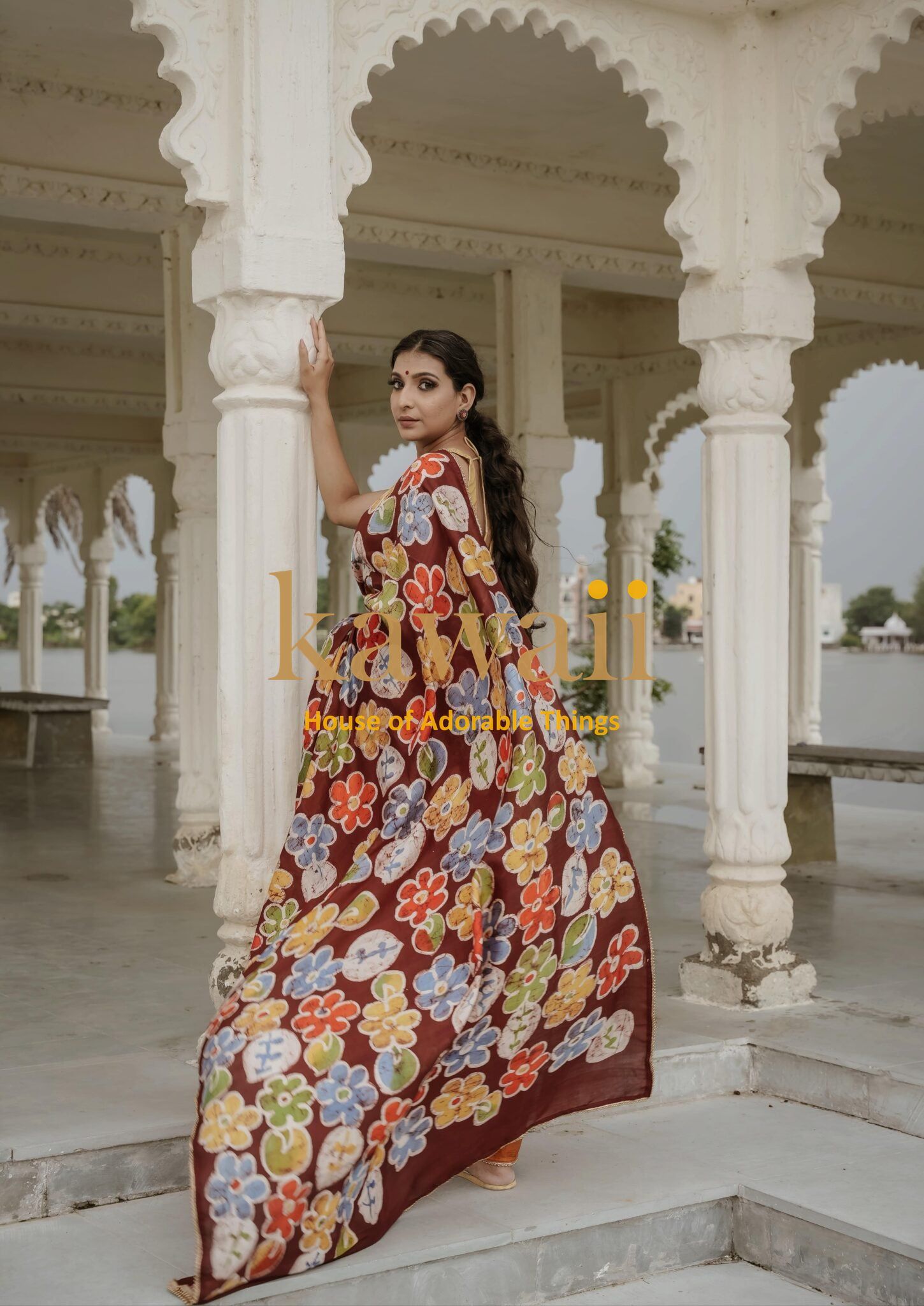 Kawaii batik saree with colorful floral patterns worn by a woman in a traditional architectural setting
