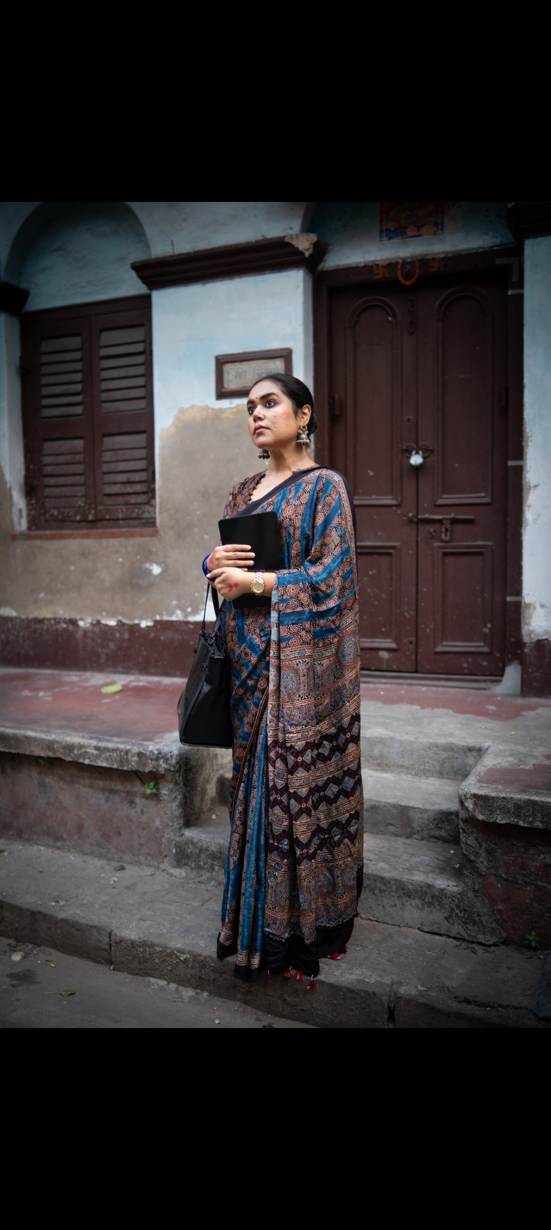 Woman wearing Kawaii best ajrakh saree in traditional blue and brown patterns standing outdoors