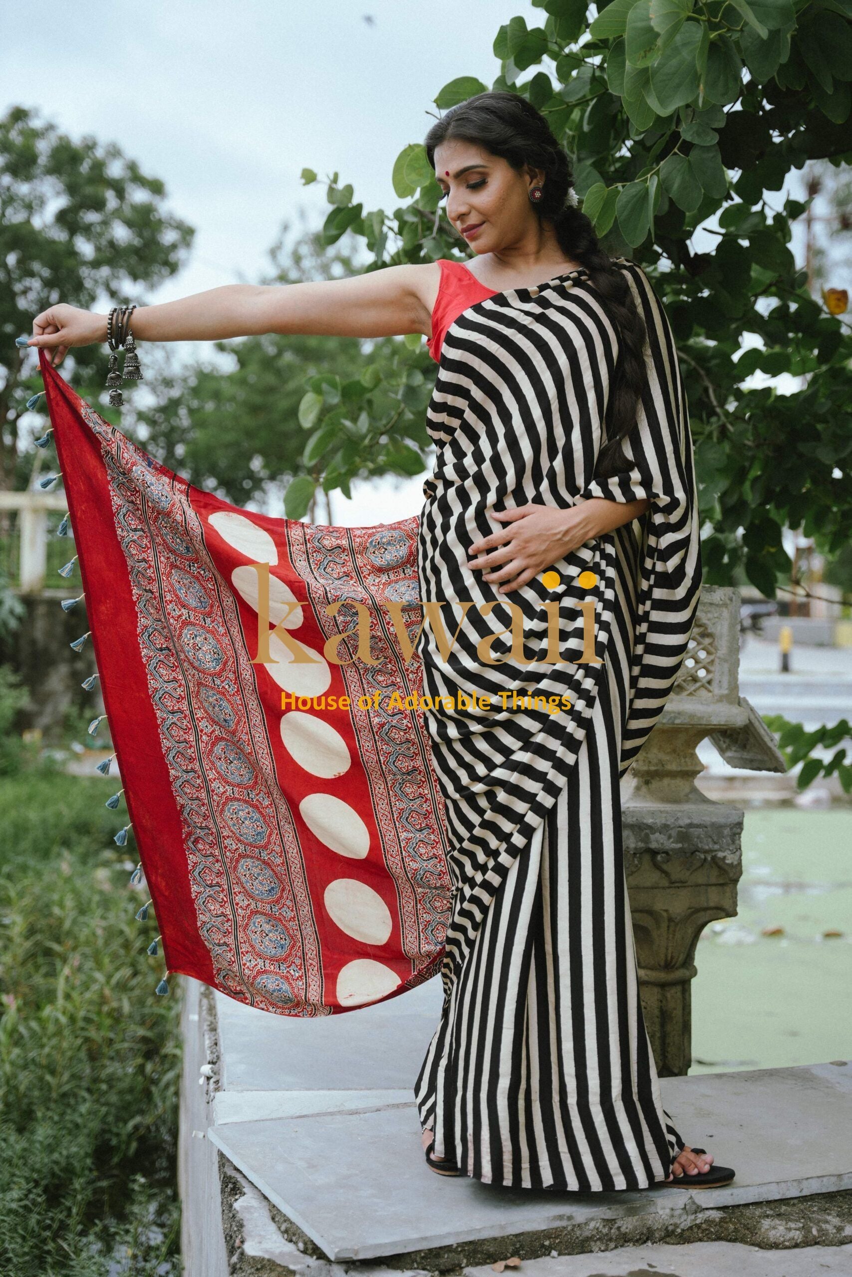 Woman wearing the best handcrafted authentic Ajrakh saree online with black and white stripes and red patterned pallu