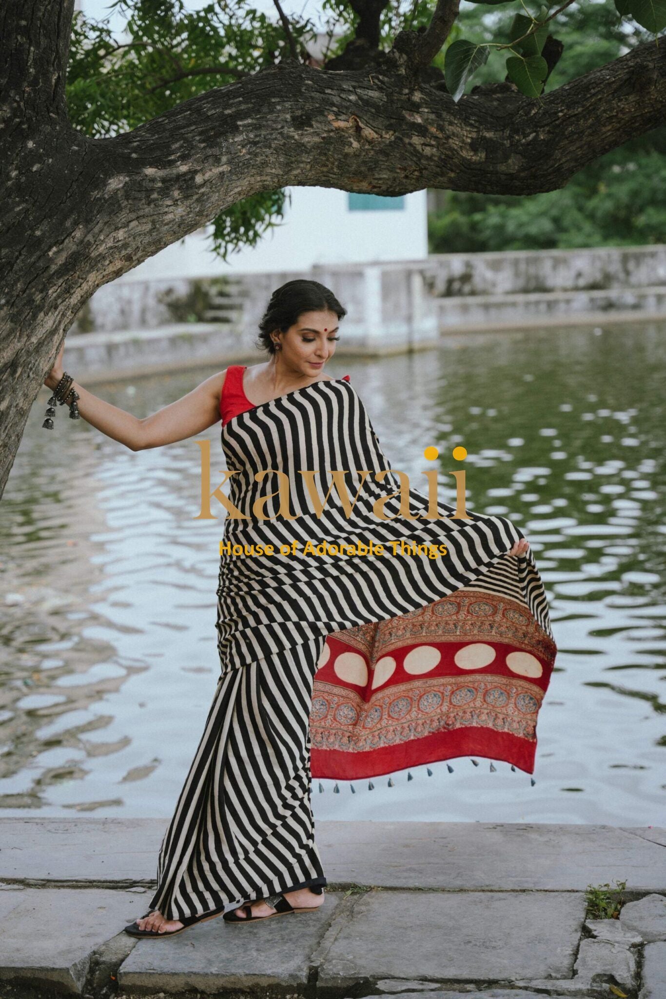 Woman wearing the Best Handcrafted Authentic Ajrakh Saree Online in black white stripes with red bordered design by Kawaii