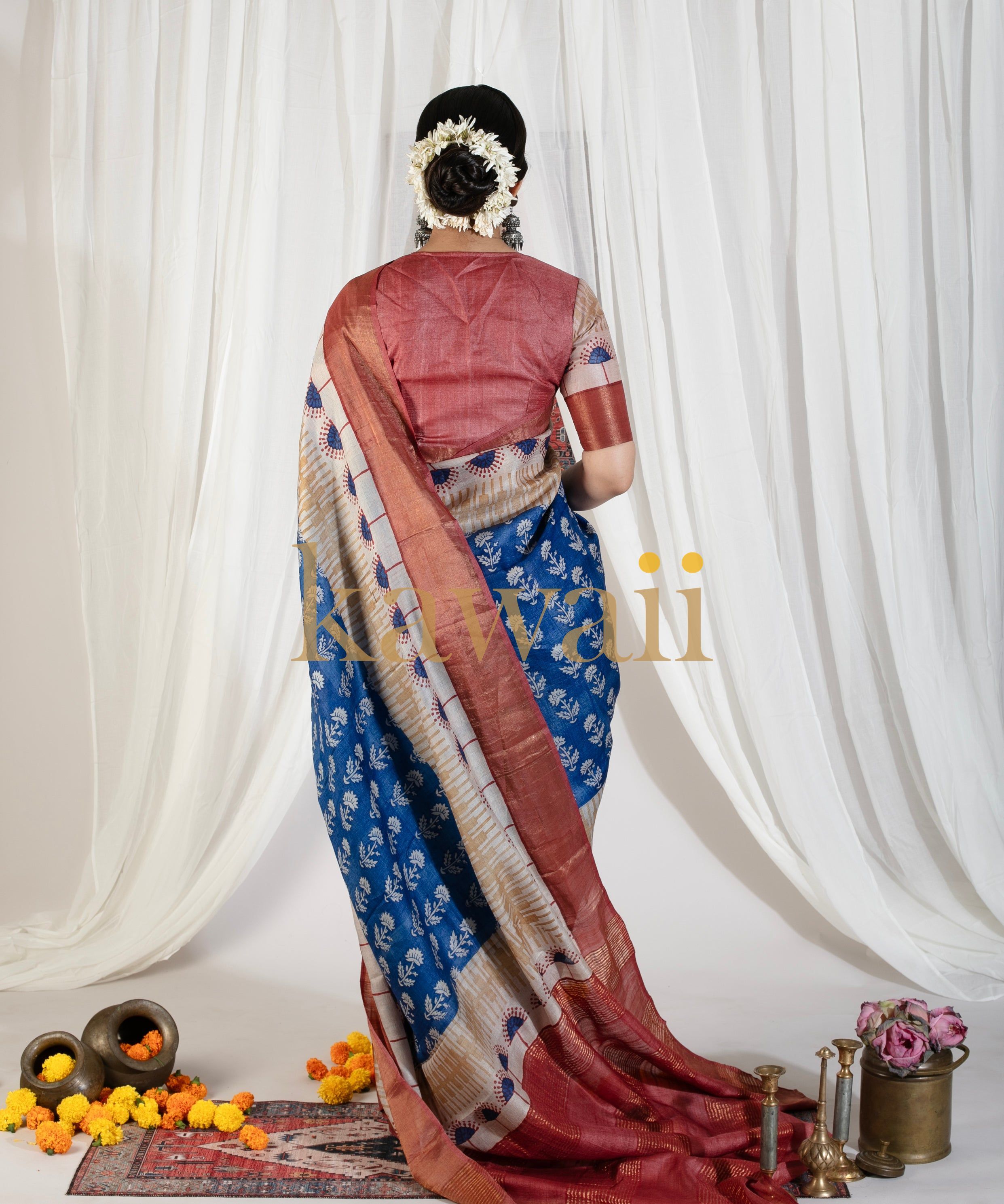 Back view of woman wearing Kawaii block print saree in blue and maroon with floral hair accessories