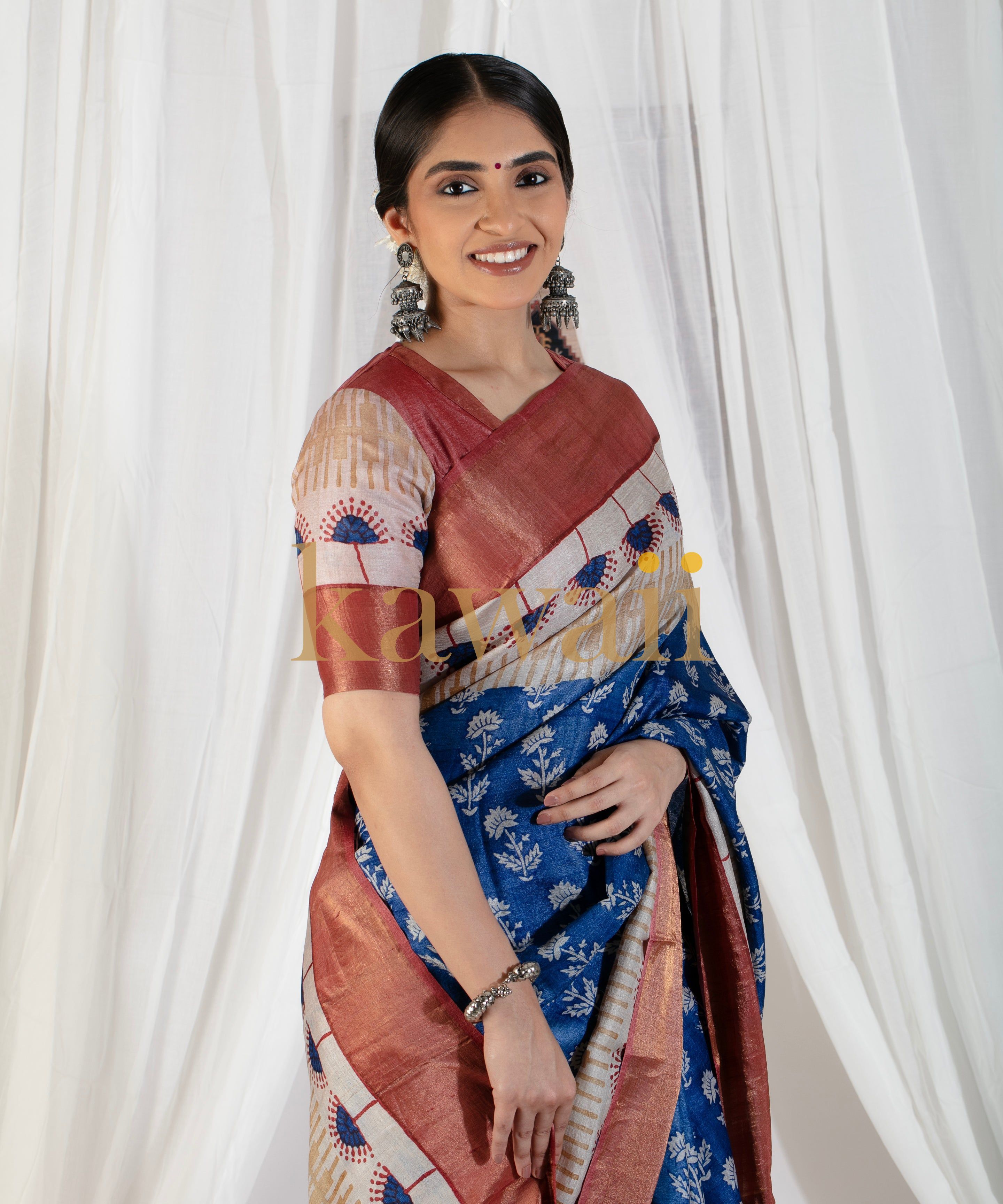 Woman wearing Kawaii block print saree with blue and maroon floral design and traditional earrings