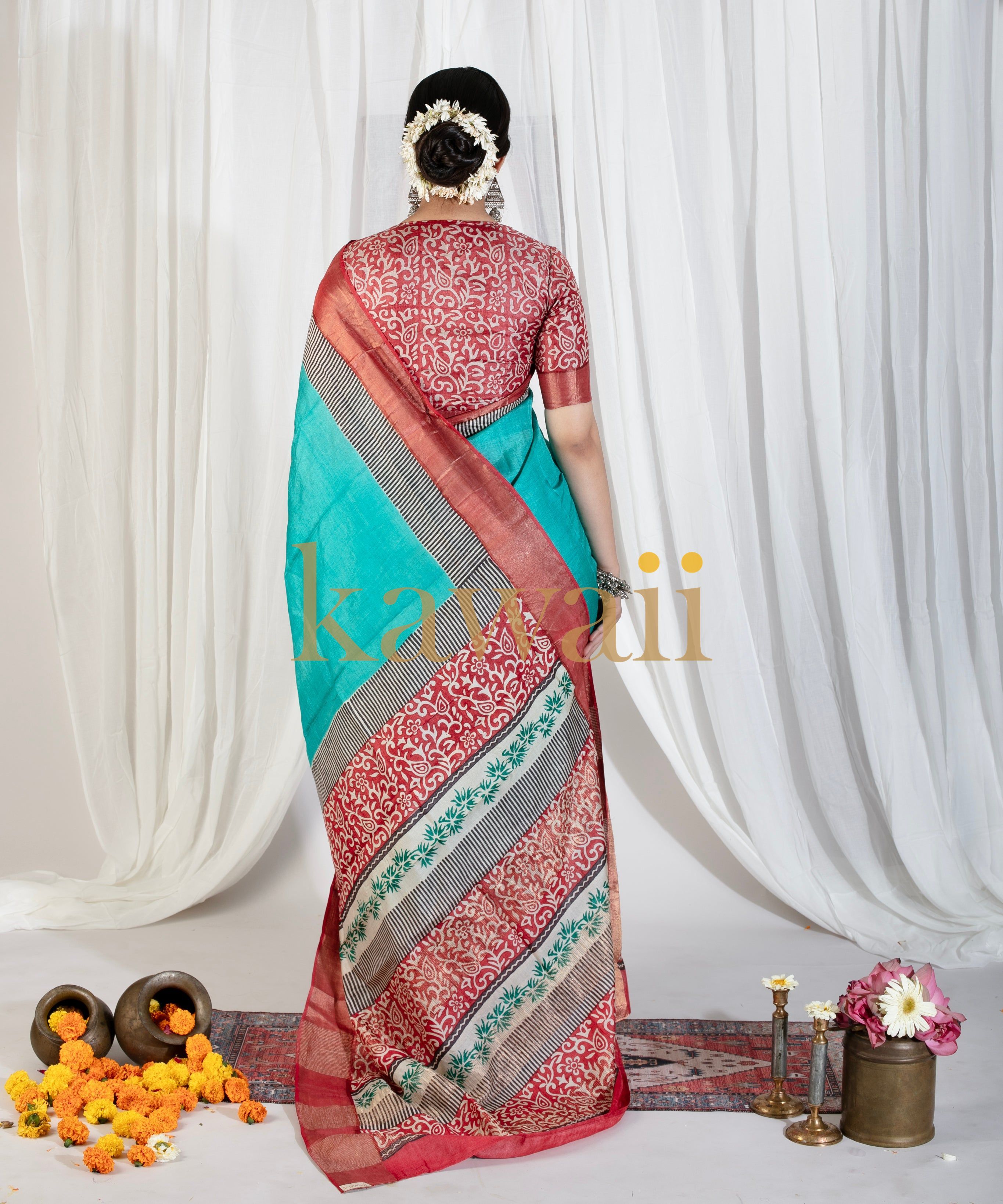 Kawaii block print saree in red and turquoise with floral and geometric patterns worn by model from back