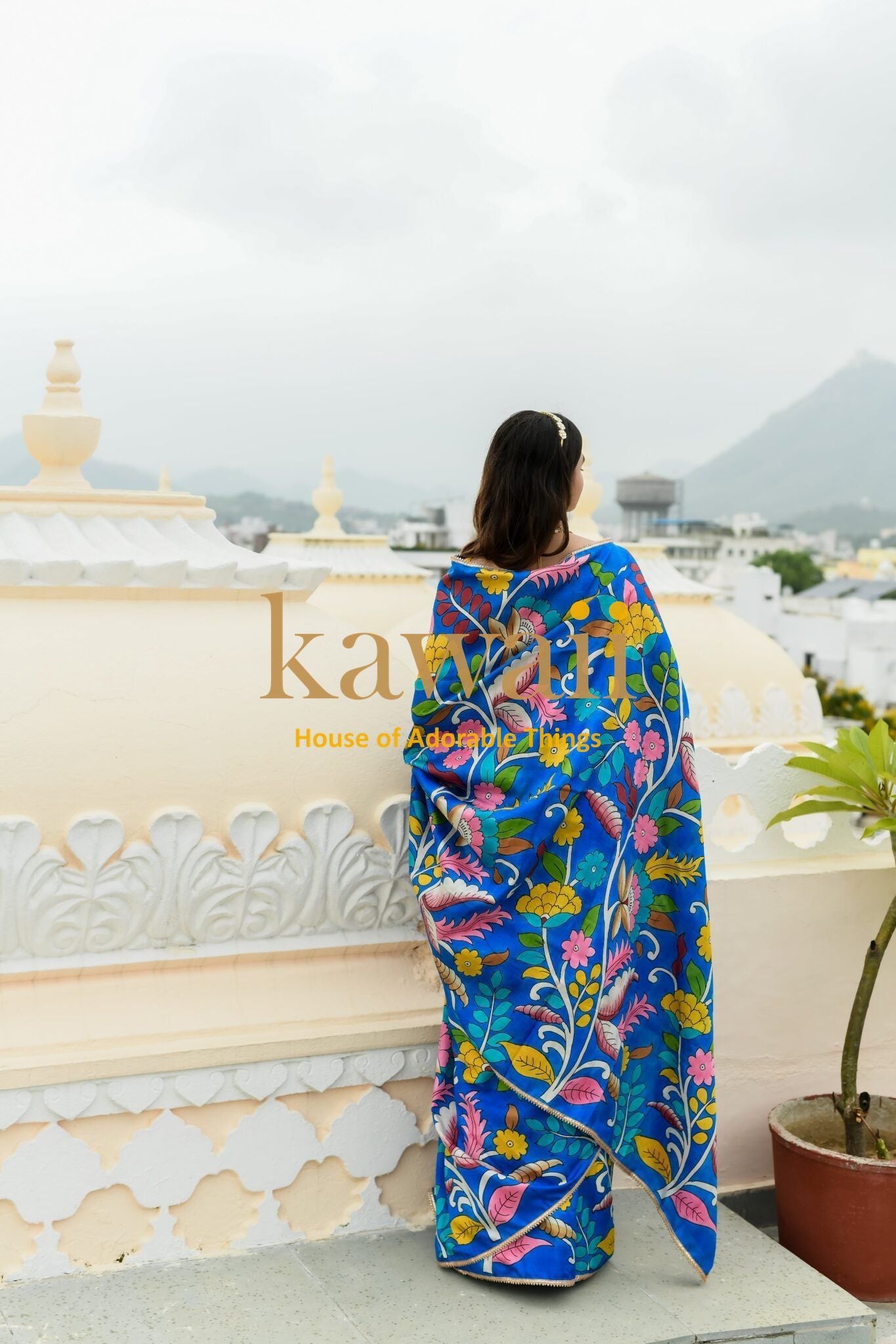 Woman wearing vibrant blue kalamkari saree with floral and bird patterns from Kawaii