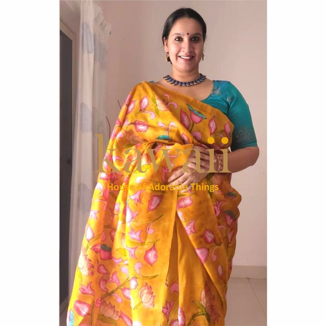 Woman wearing a yellow and pink floral kalamkari saree by Kawaii with a teal blouse