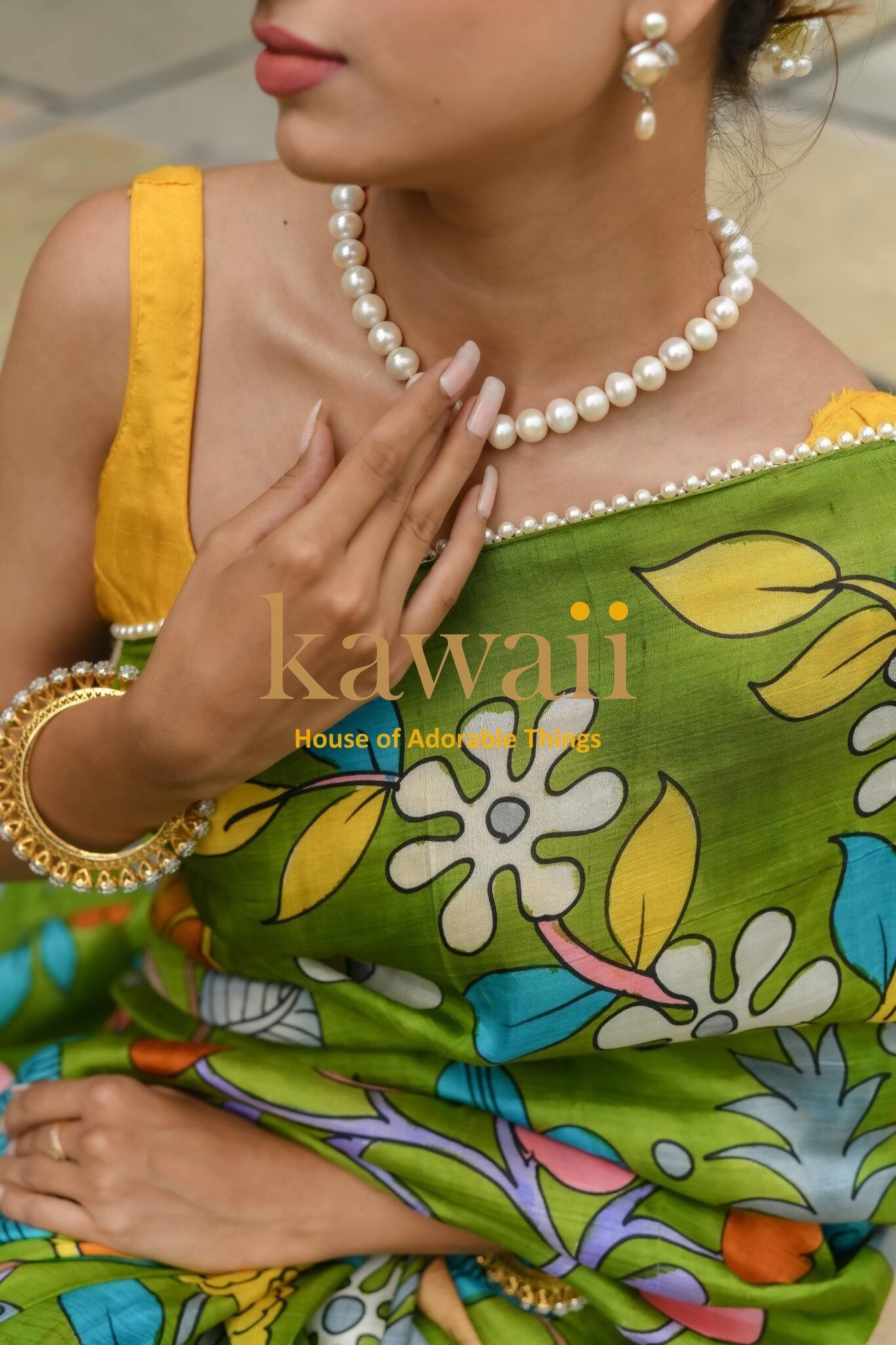 Kawaii kalamkari saree with vibrant floral green and blue patterns worn with pearl jewelry