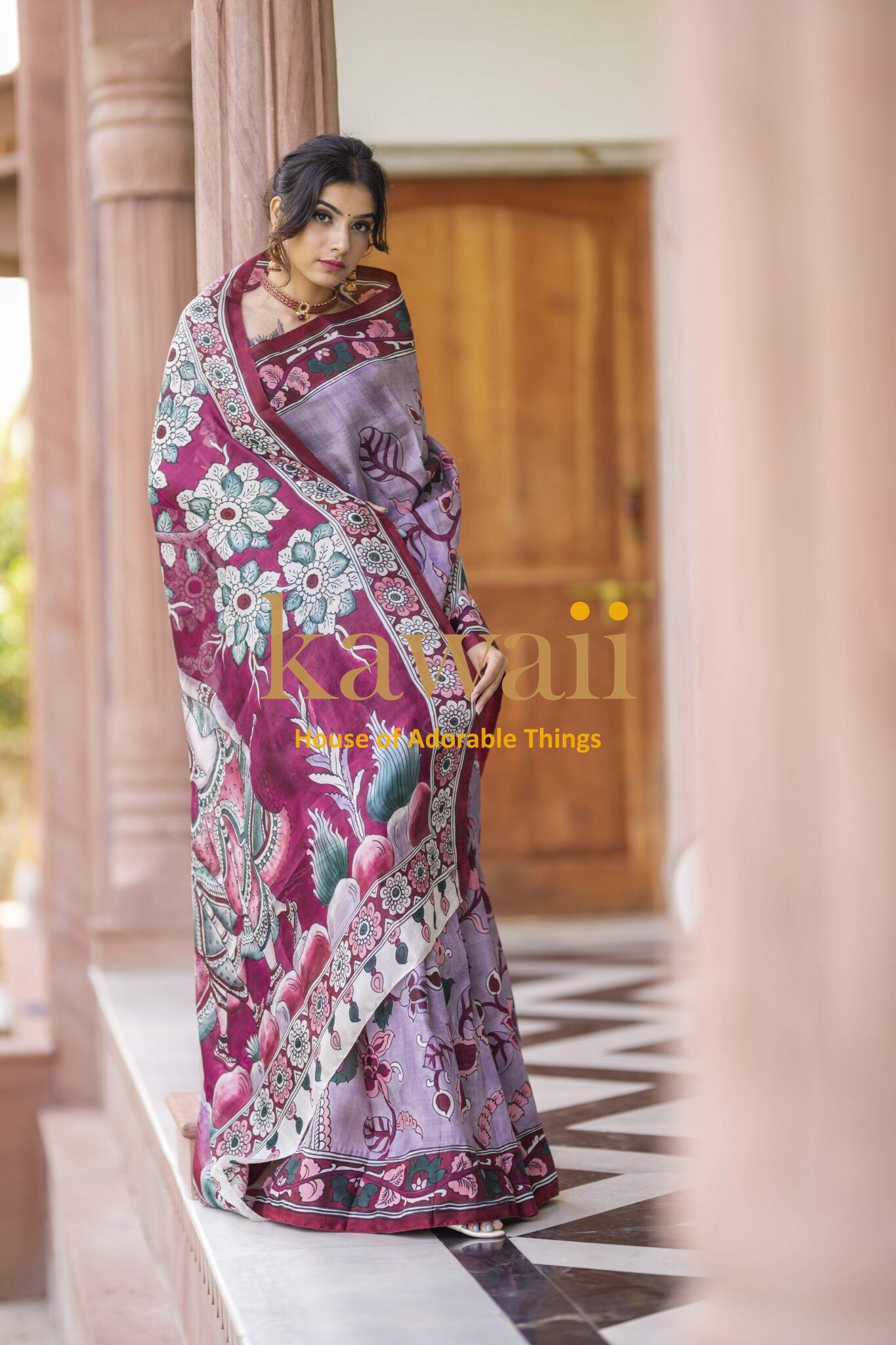 Woman wearing a purple and pink floral patterned kalamkari saree by Kawaii